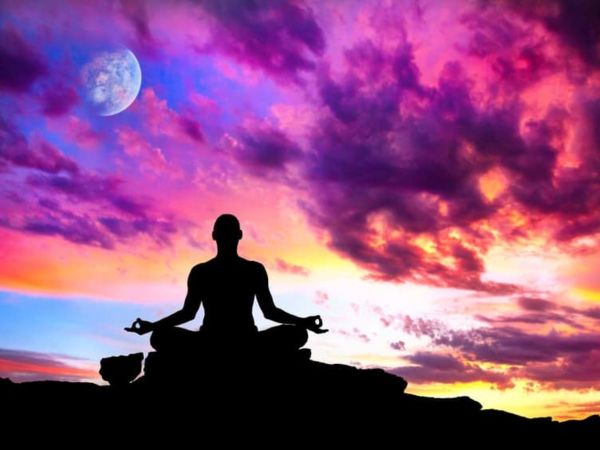 Silhouette of person meditating during sunset with colorful sky and moon.