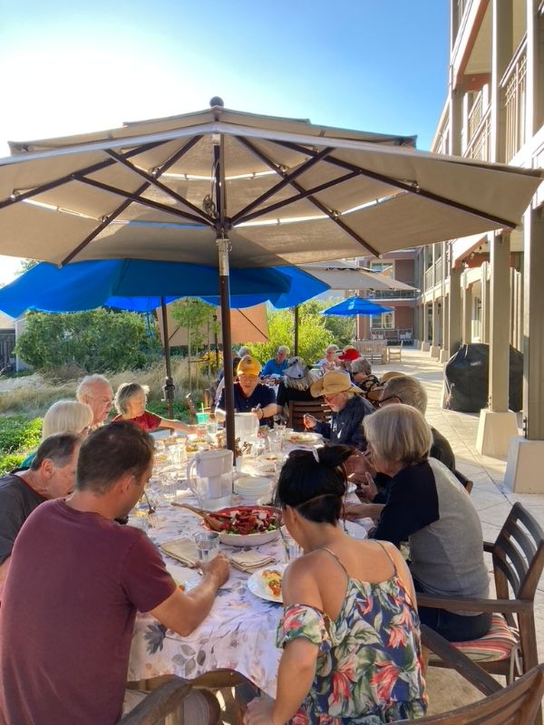 People enjoying outdoor meal under umbrellas at Mountain View Cohousing.