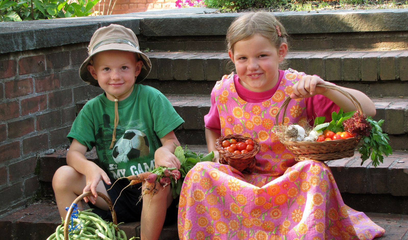 Two children with baskets of eggs and flowers on steps.