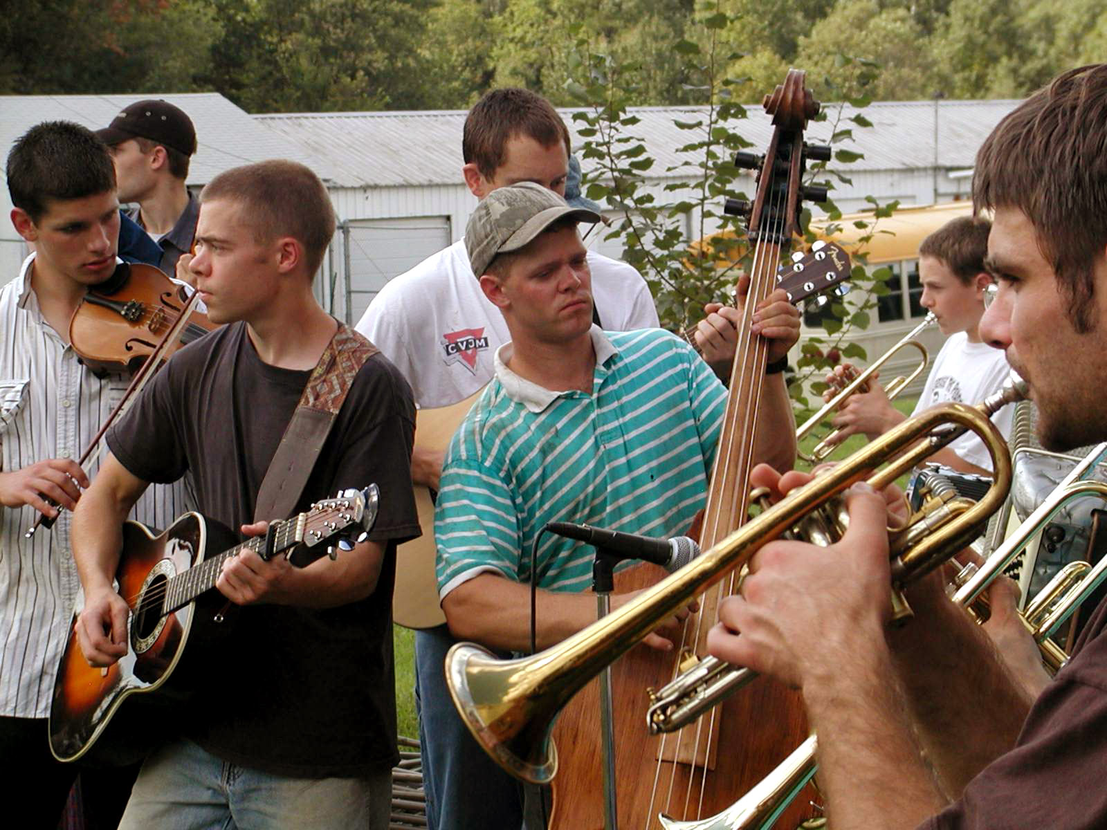 Group of young people playing musical instruments outdoors at community event.