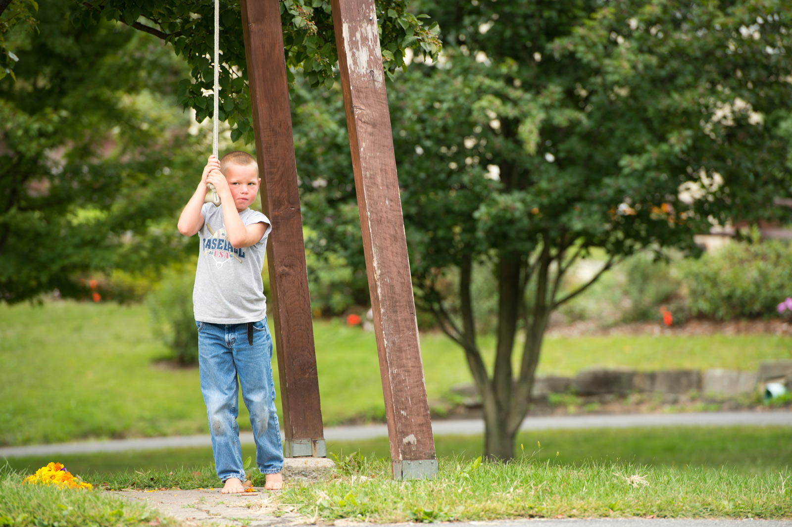 Child swinging on wooden swing set in community park.