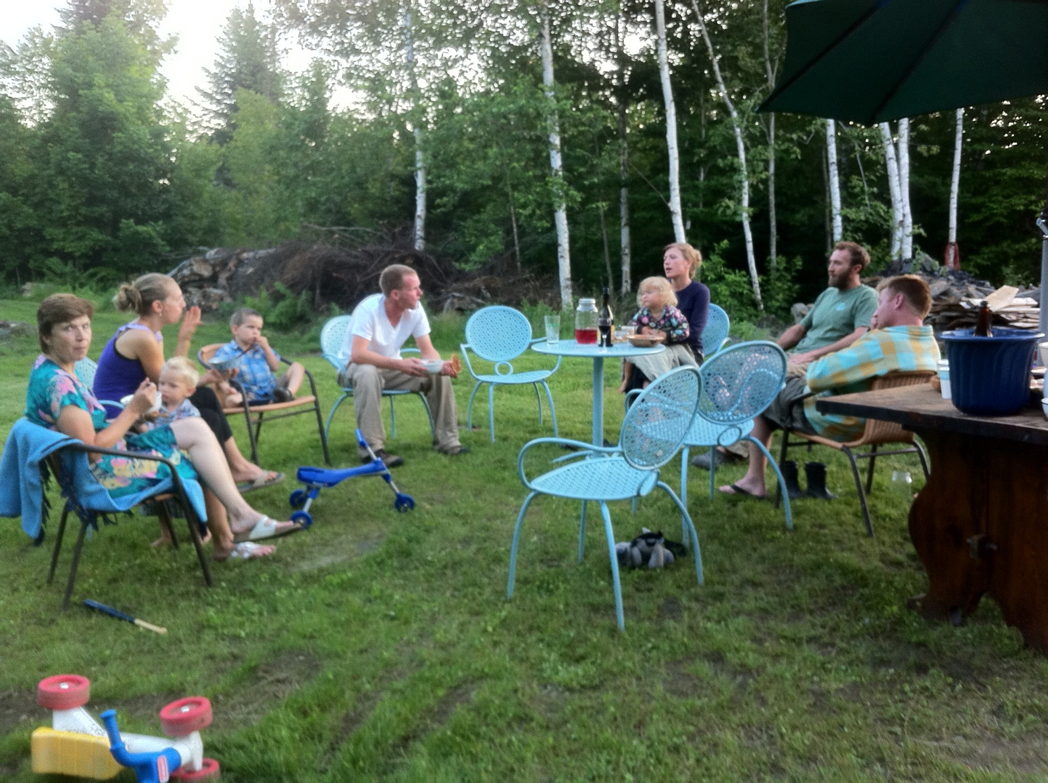Family and friends enjoying outdoor gathering in a lush green setting.