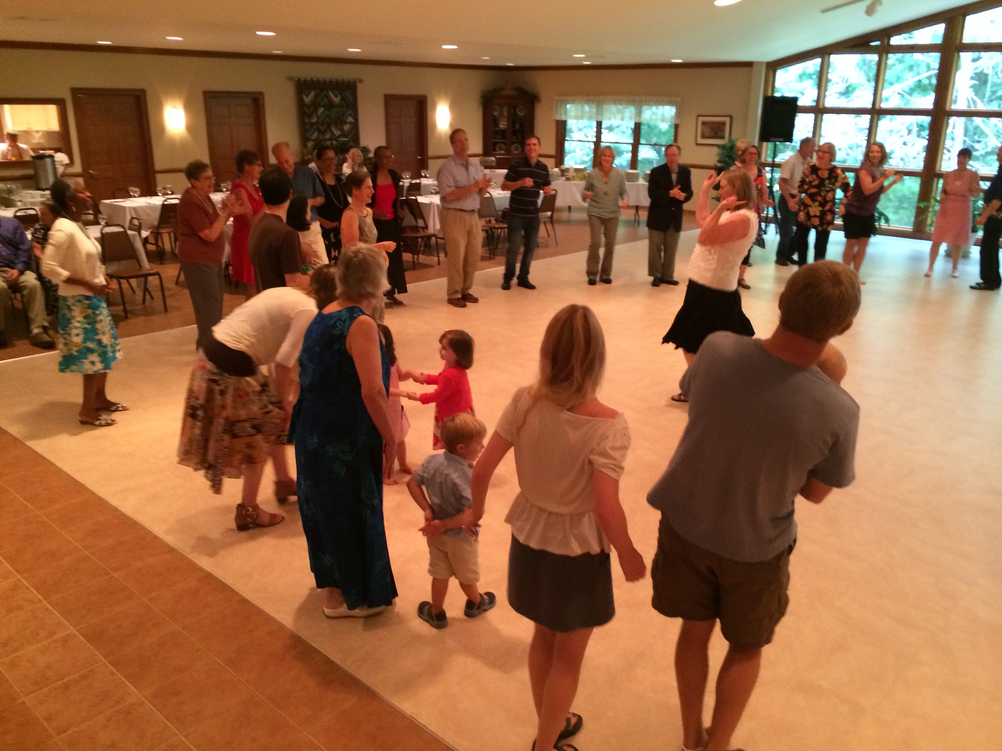 People dancing and socializing at a community event in a spacious hall.