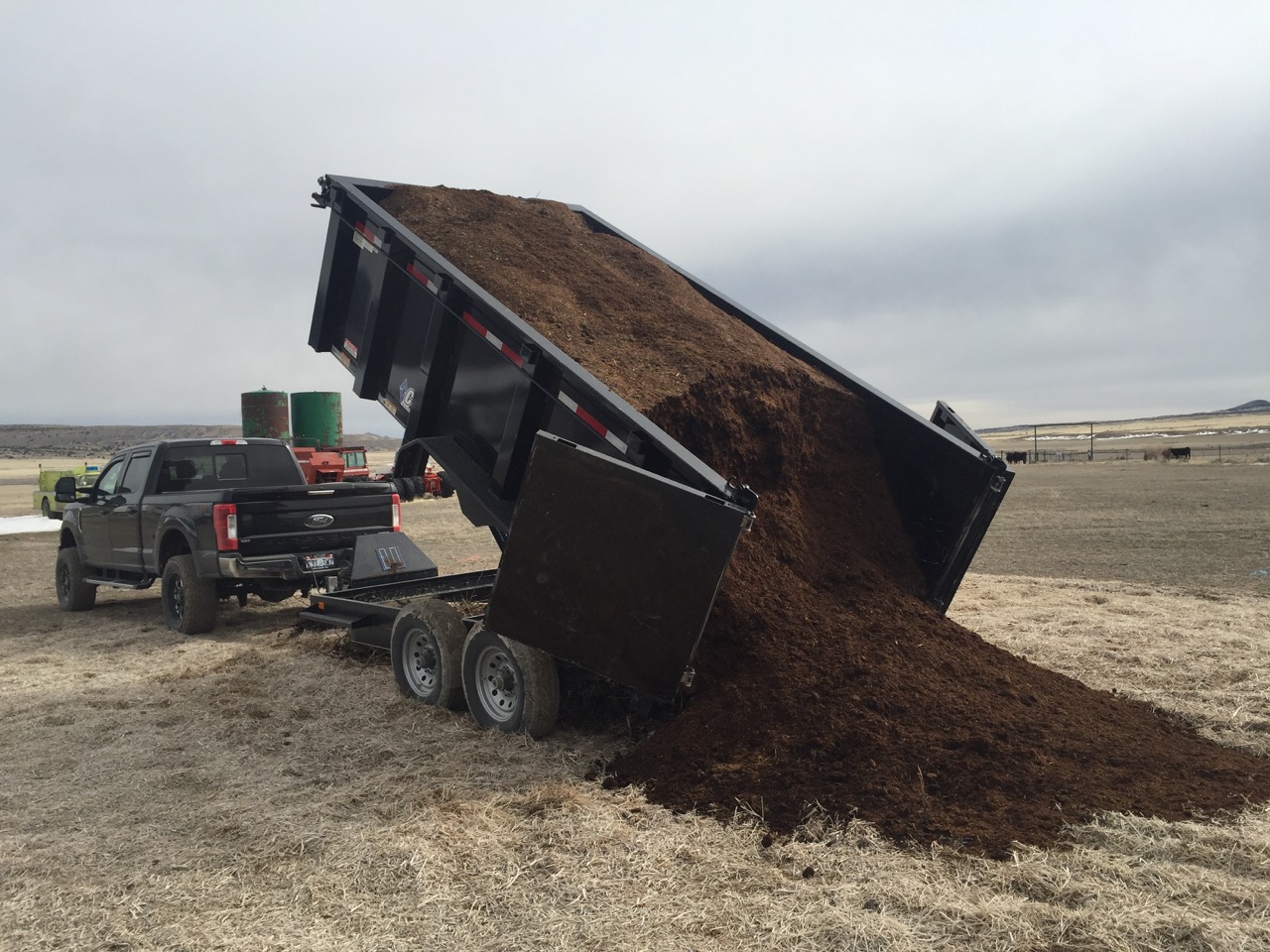 Dump truck unloading soil on a rural farm for homesteading.