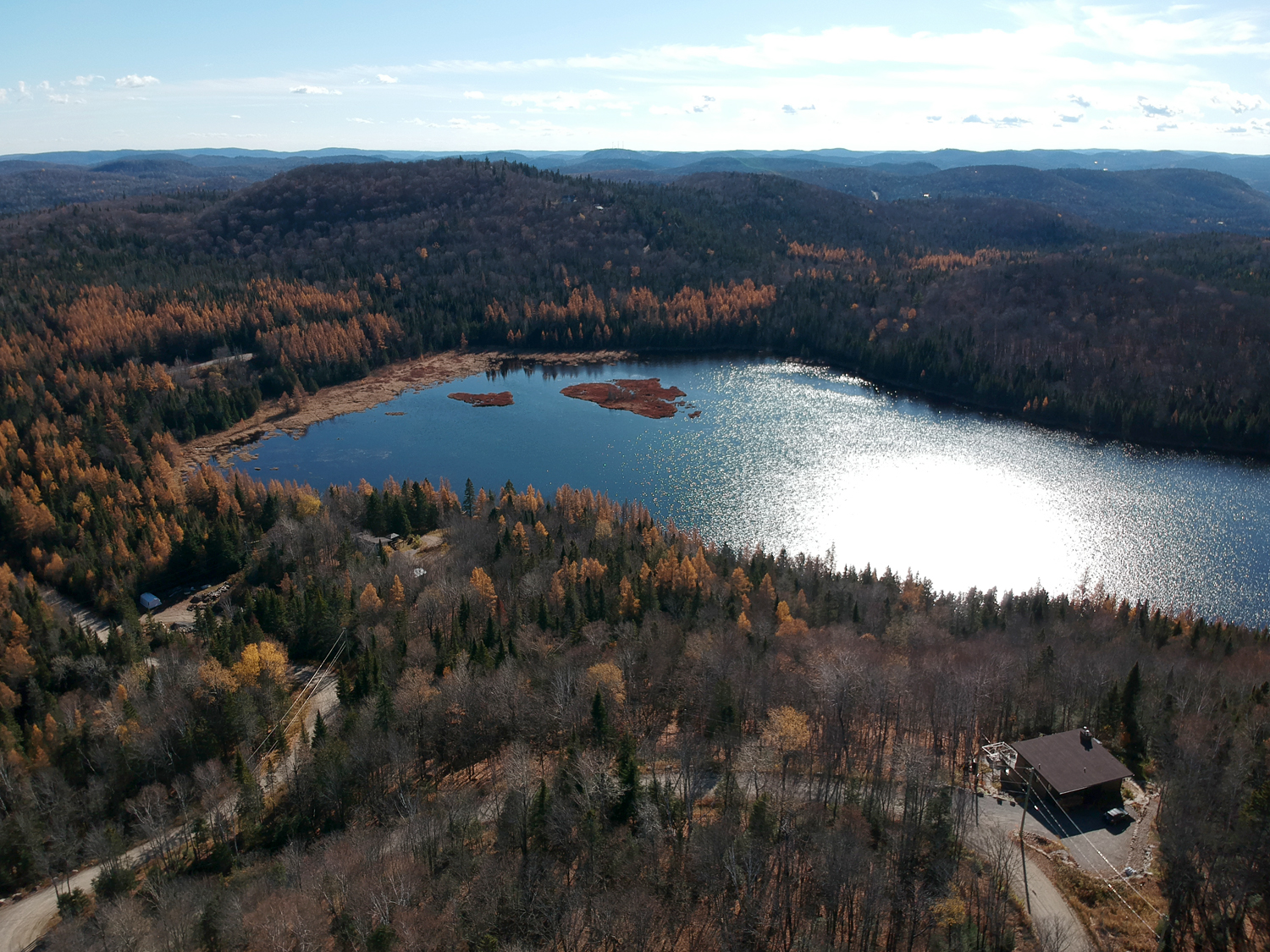 Aerial view of a forested lake with surrounding trees and hills.