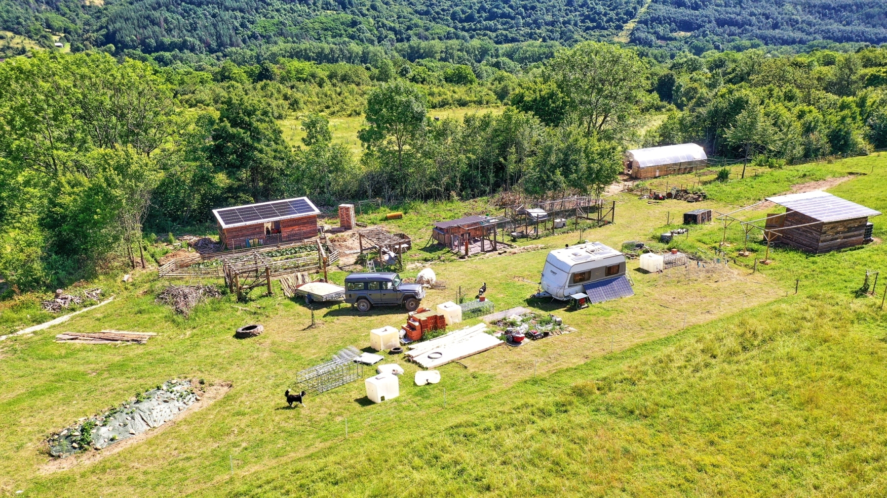 Aerial view of a sustainable homestead with solar panels and eco-friendly structures.