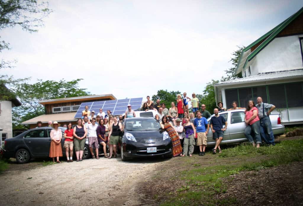 Group of people at Dancing Rabbit Ecovillage with solar panels in background.