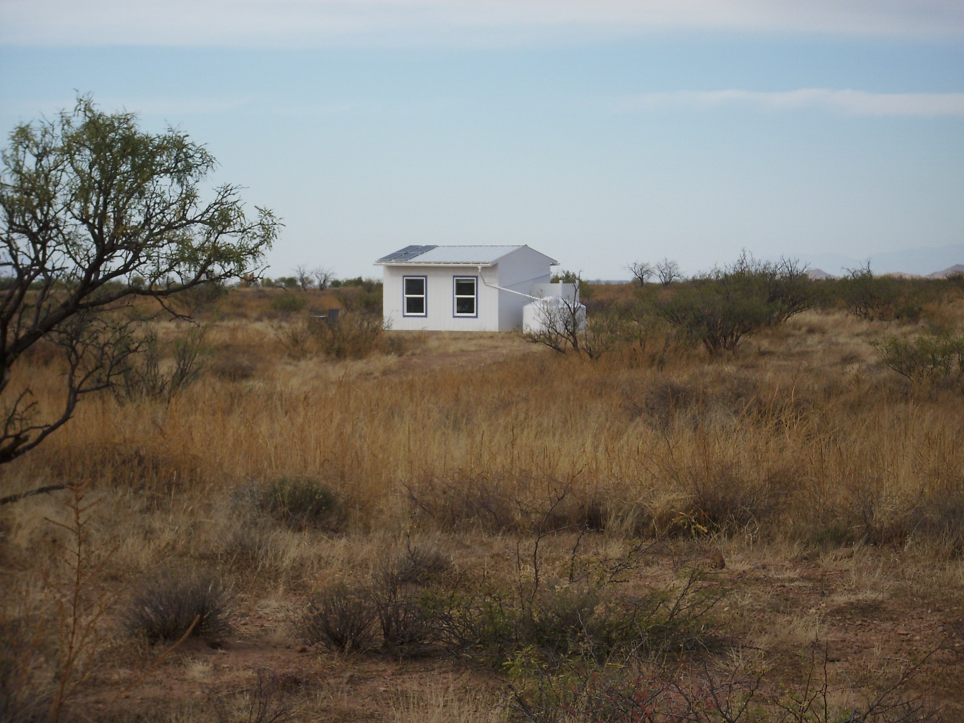 Small white house in a dry, open landscape with sparse vegetation.