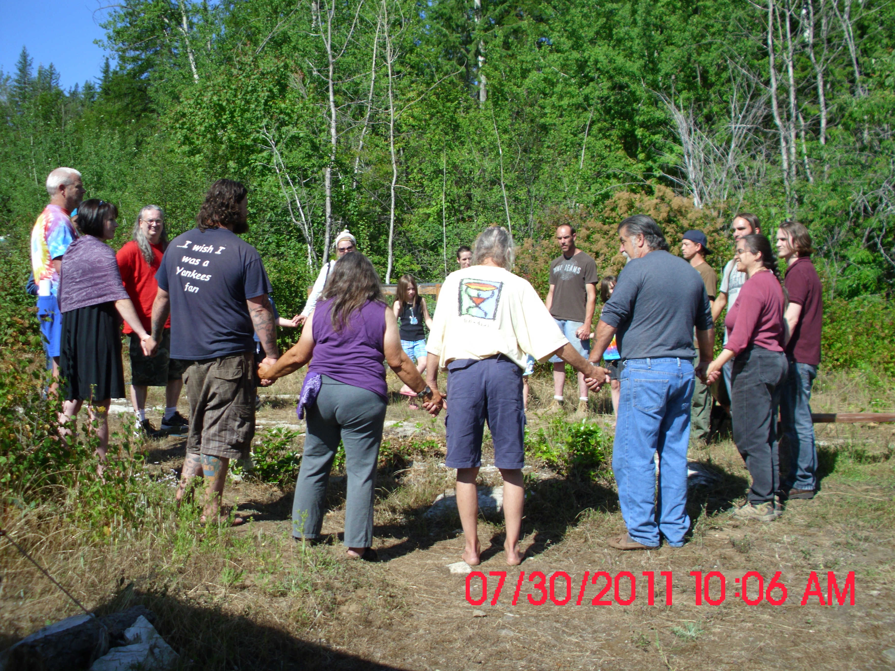 Group of people holding hands in circle at Earth Rising Sanctuary.