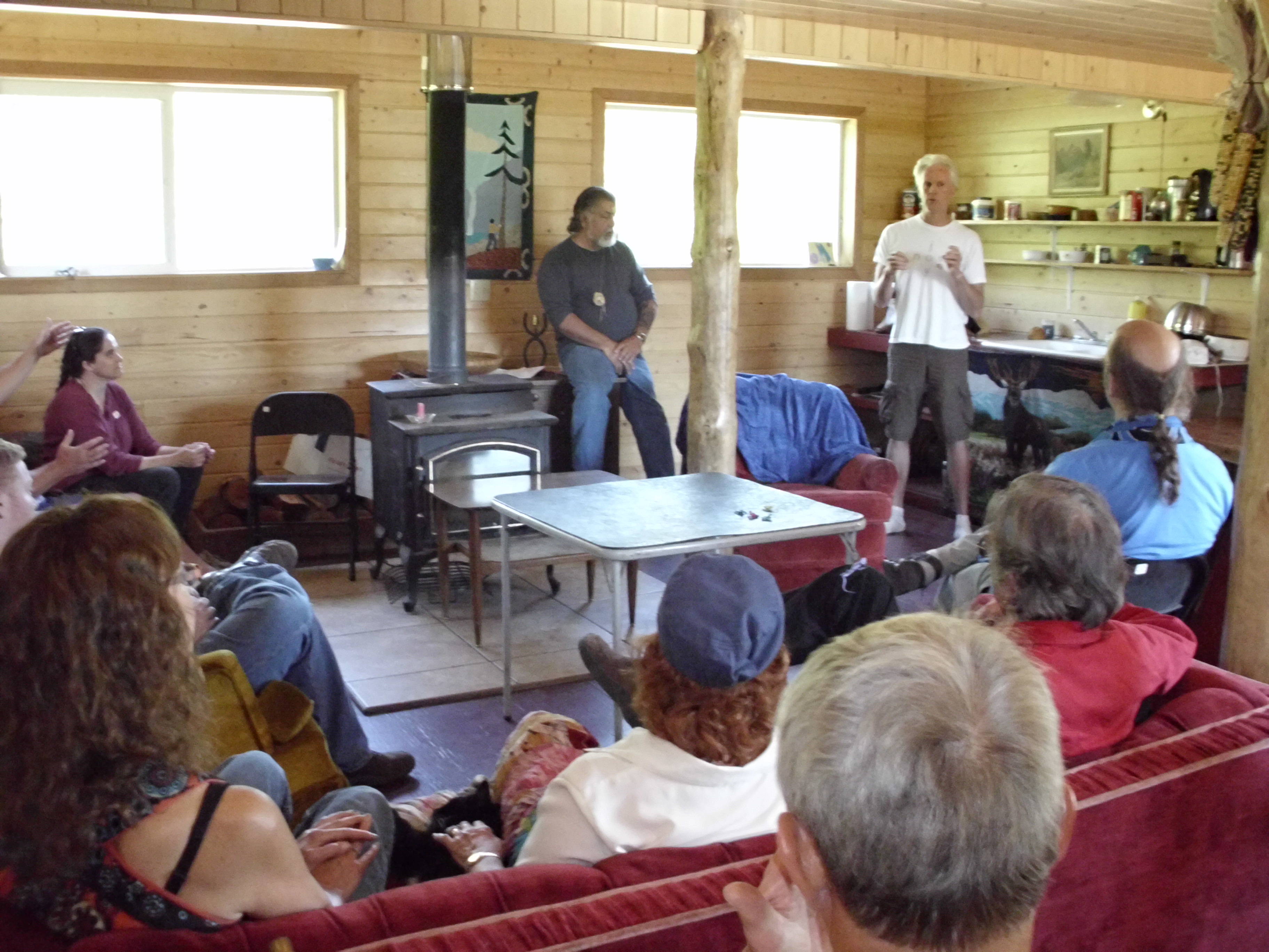 People attending a community meeting in a cozy wooden room at Earth Rising Sanctuary.