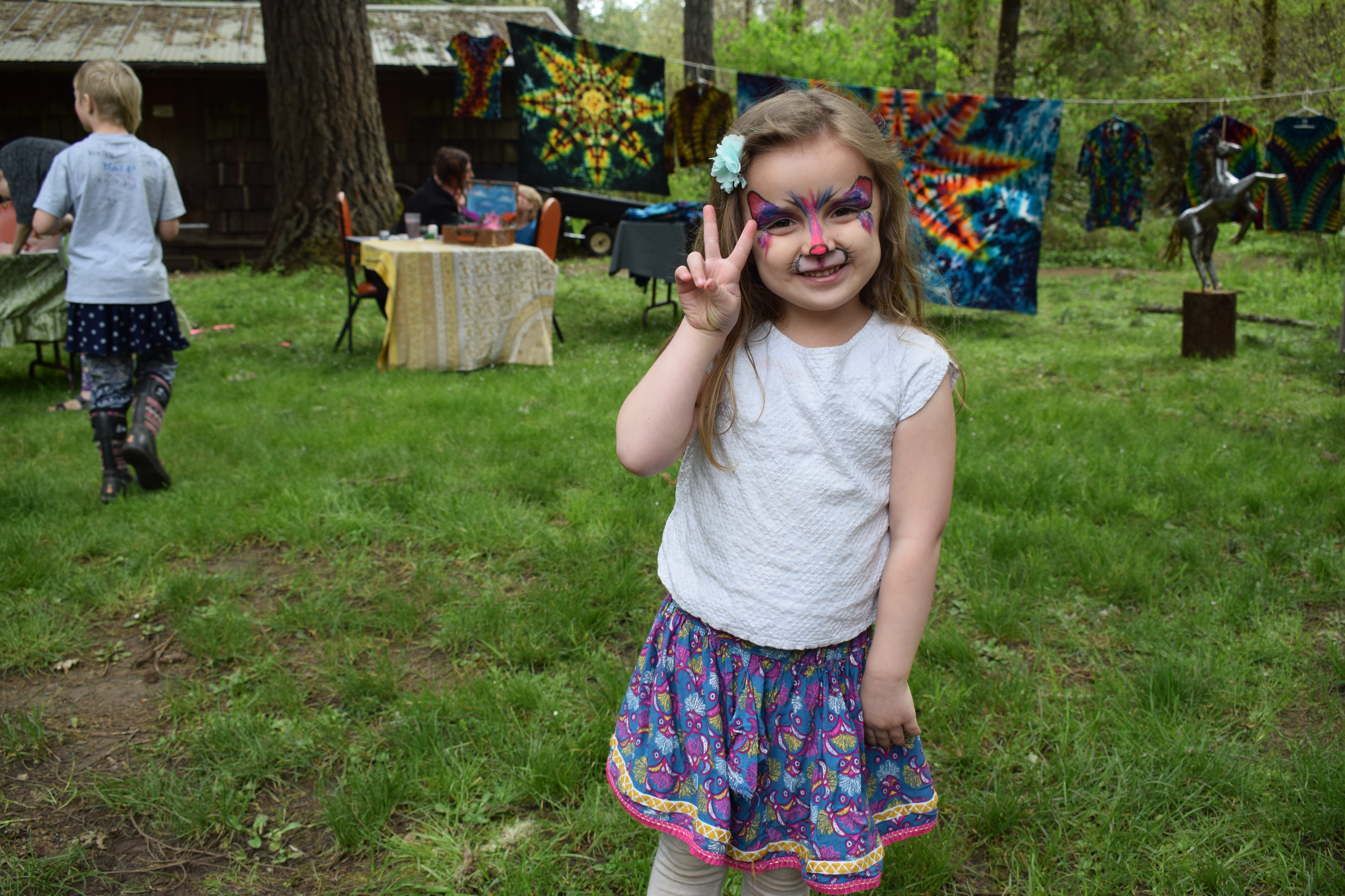 Girl with face paint at outdoor community event in a park setting.