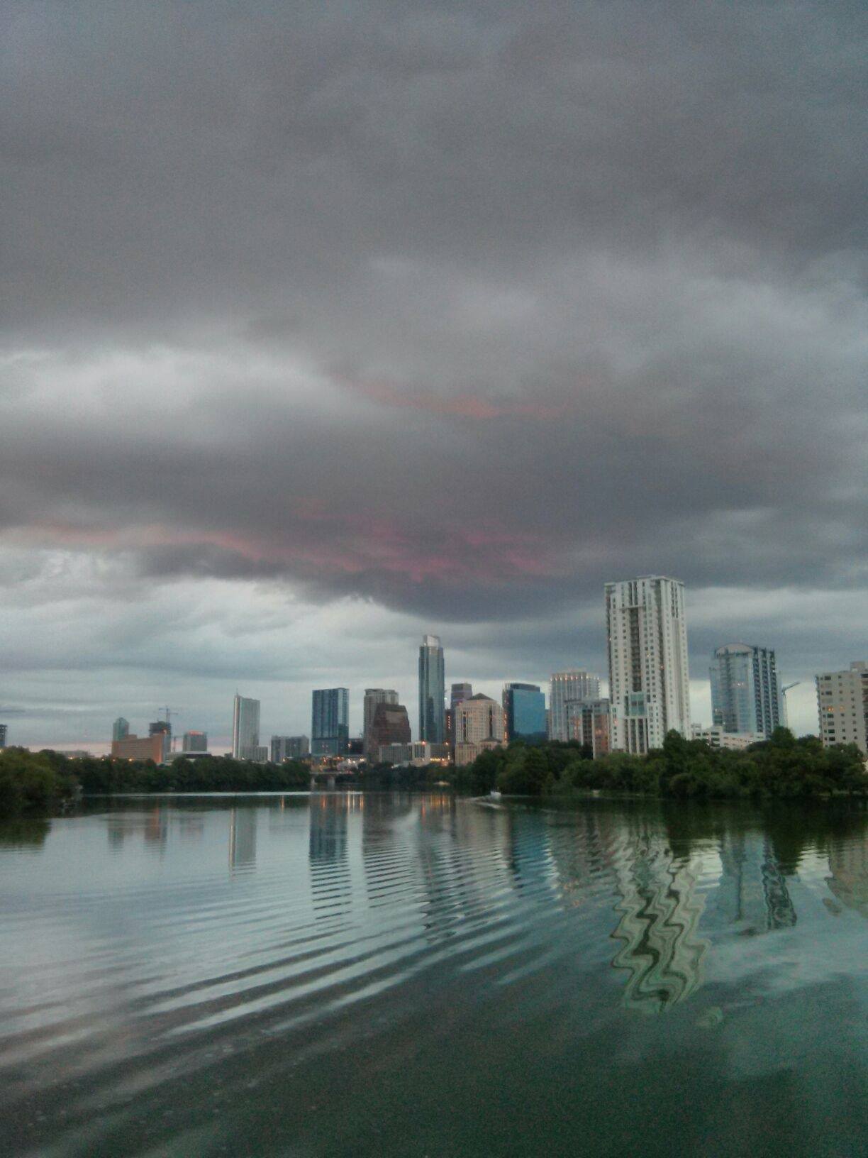 Urban cityscape with tall buildings under dark storm clouds.