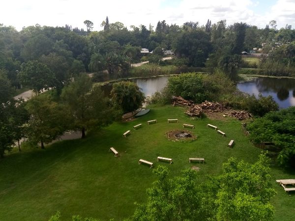 Community gathering area with benches around a fire pit near a pond.