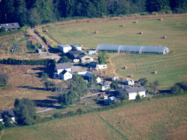 Aerial view of a sustainable community farm with greenhouses and fields.
