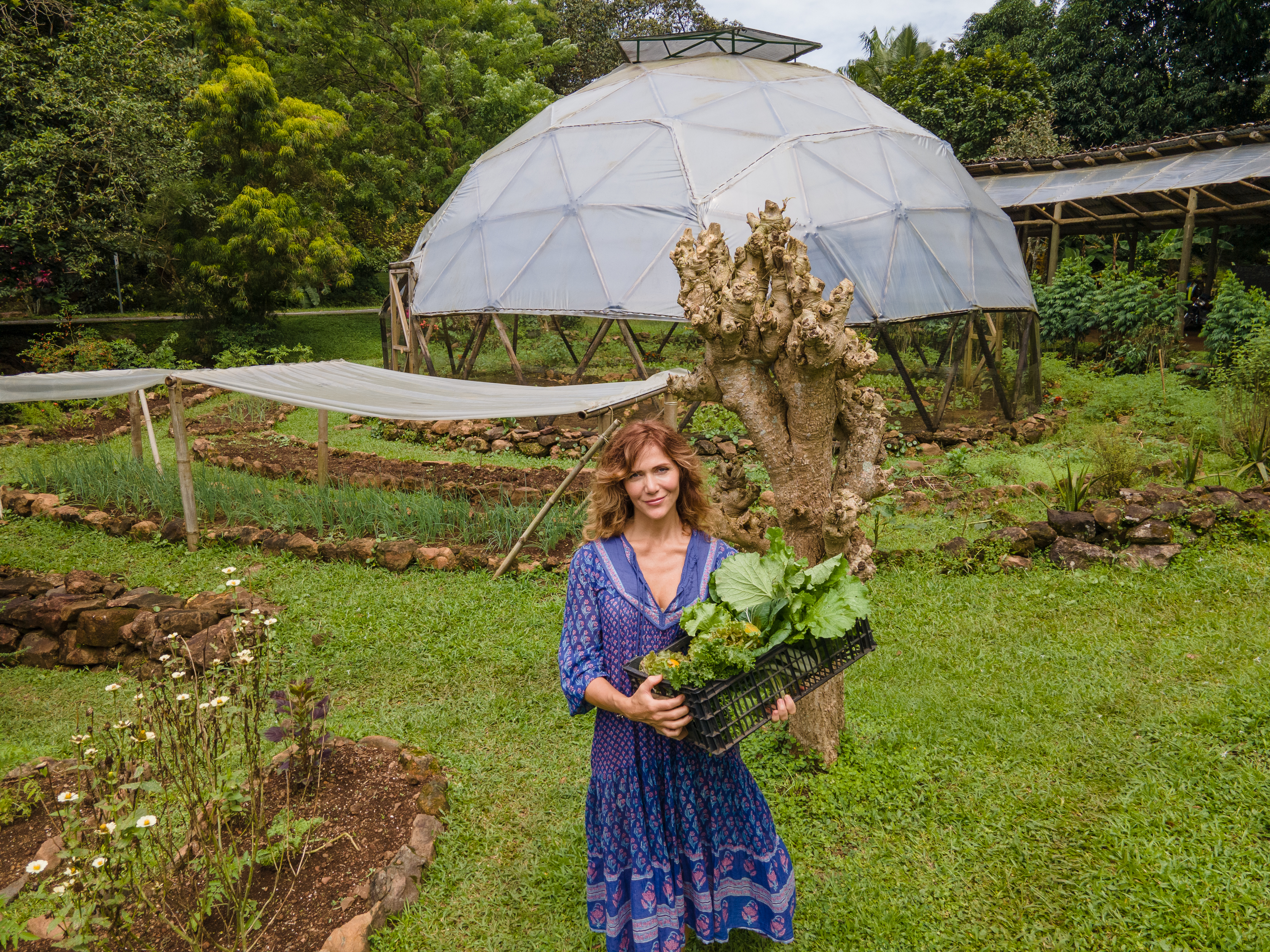 Woman holding fresh vegetables in eco-friendly community garden in Costa Rica.