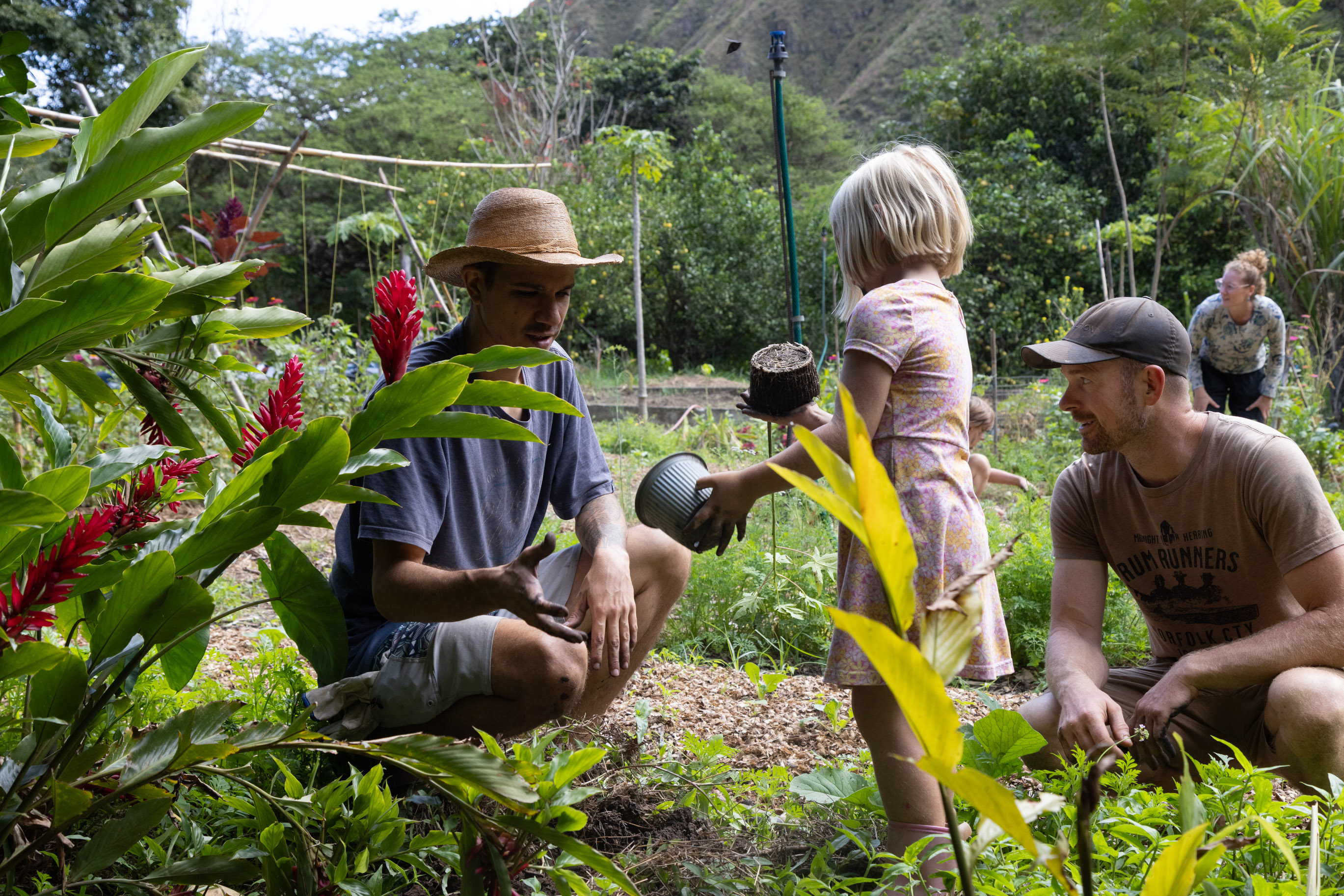 People gardening at Finca Sagrada, community farm with children and adults.