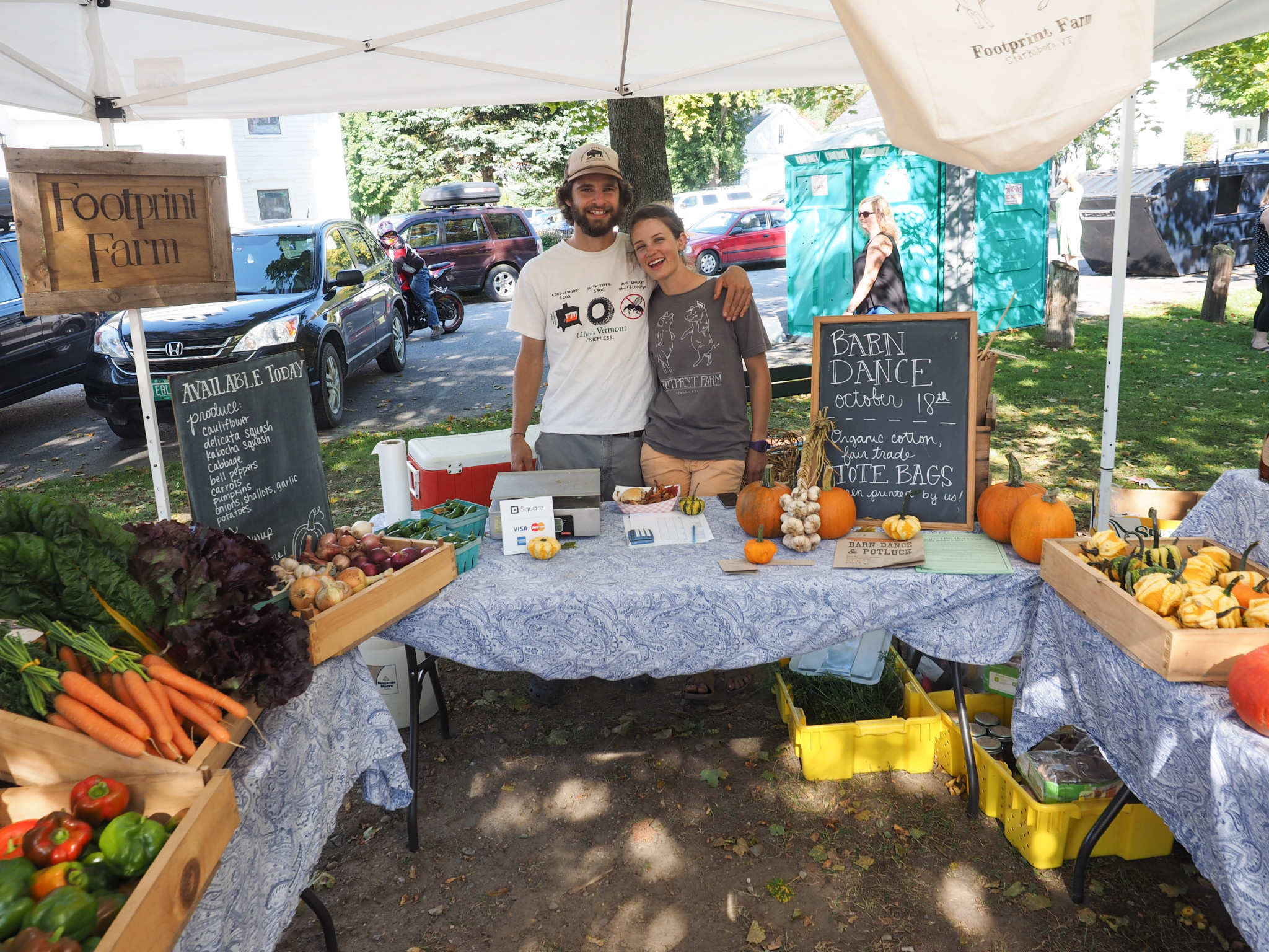 Footprint Farm booth selling fresh vegetables and pumpkins at community event.