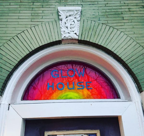Colorful GlowHouse sign with rainbow background and blue text.