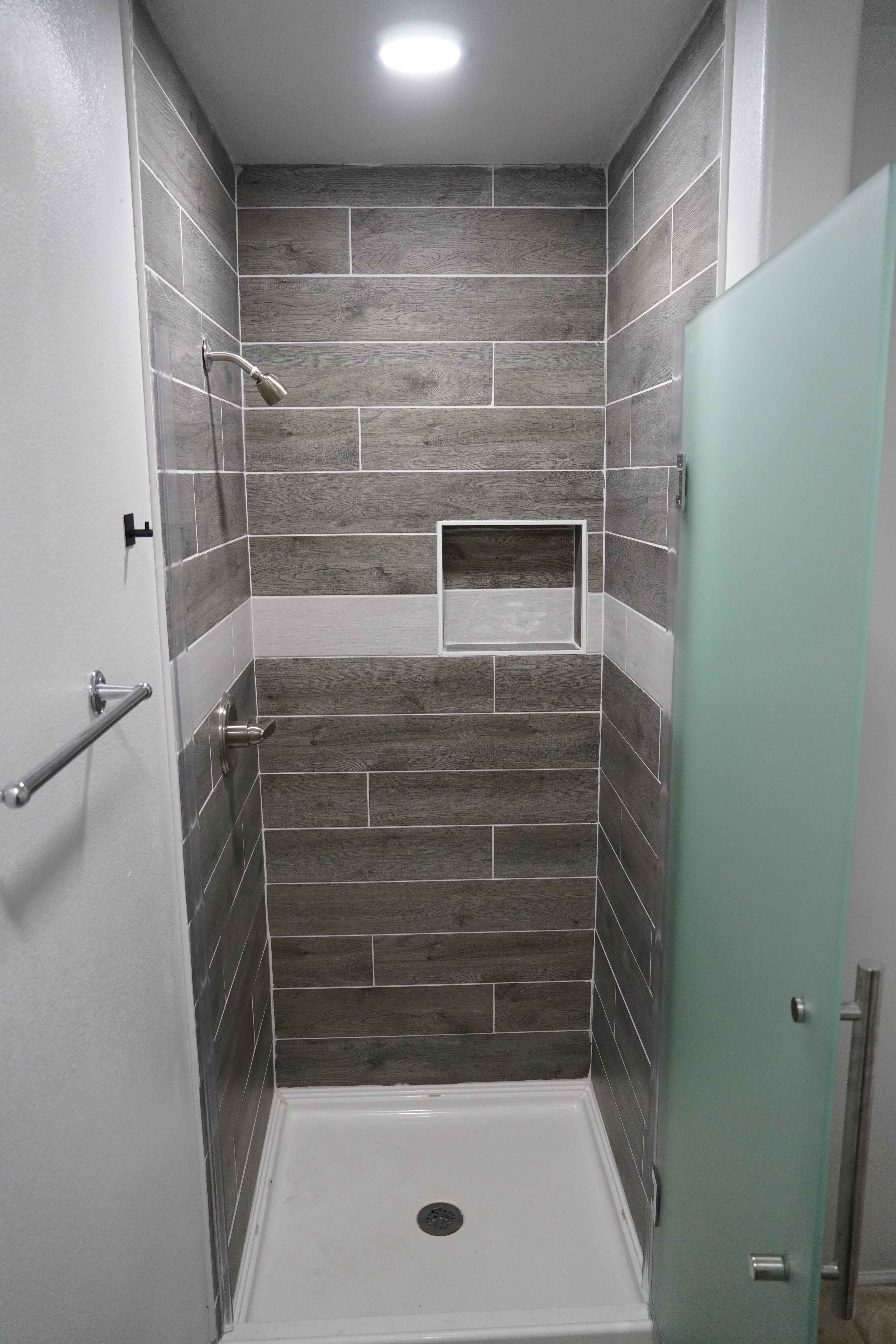 Contemporary shower with gray tiles and frosted glass door.
