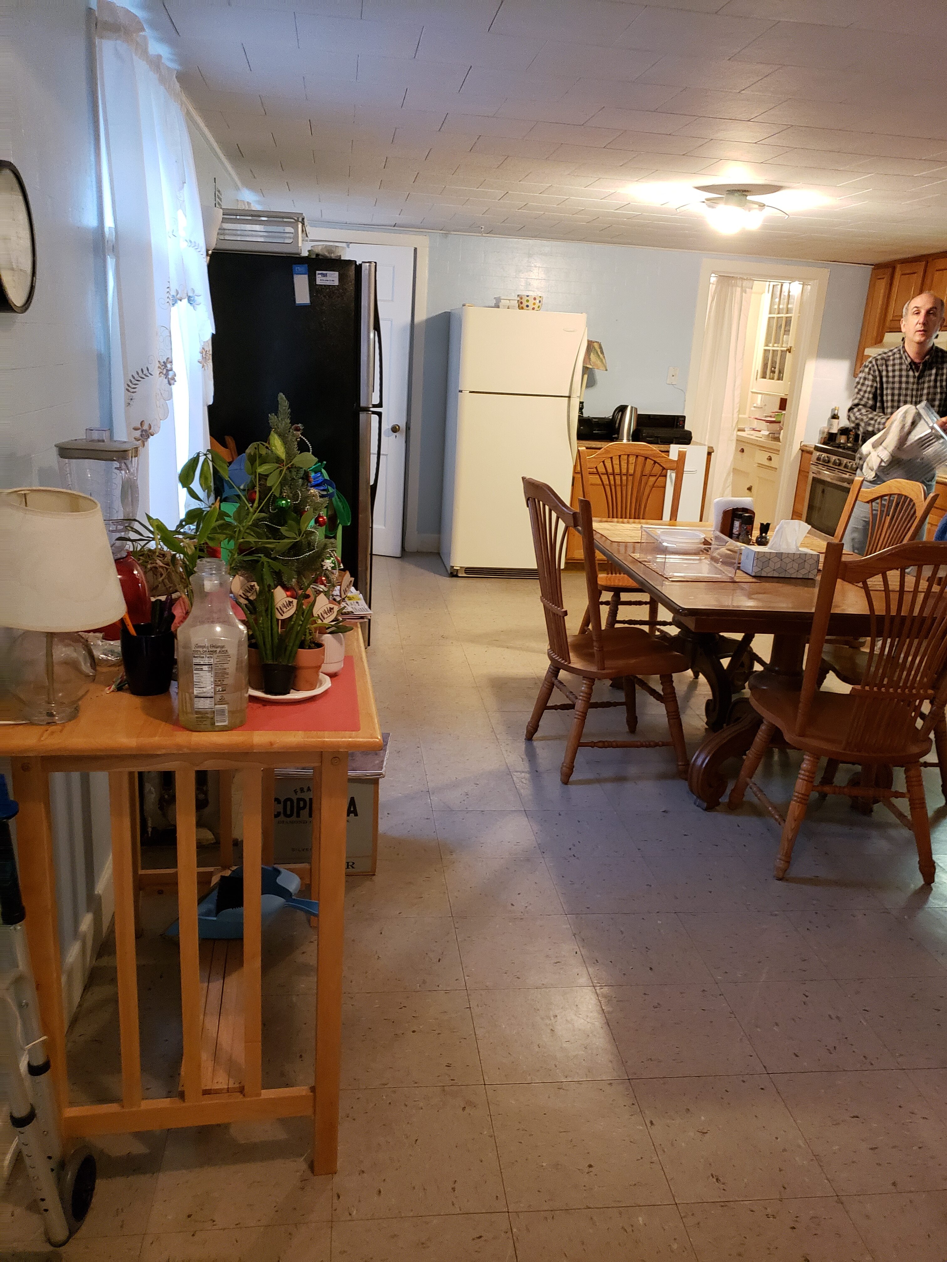 Interior of a home with a dining table, refrigerator, and a person in the background.
