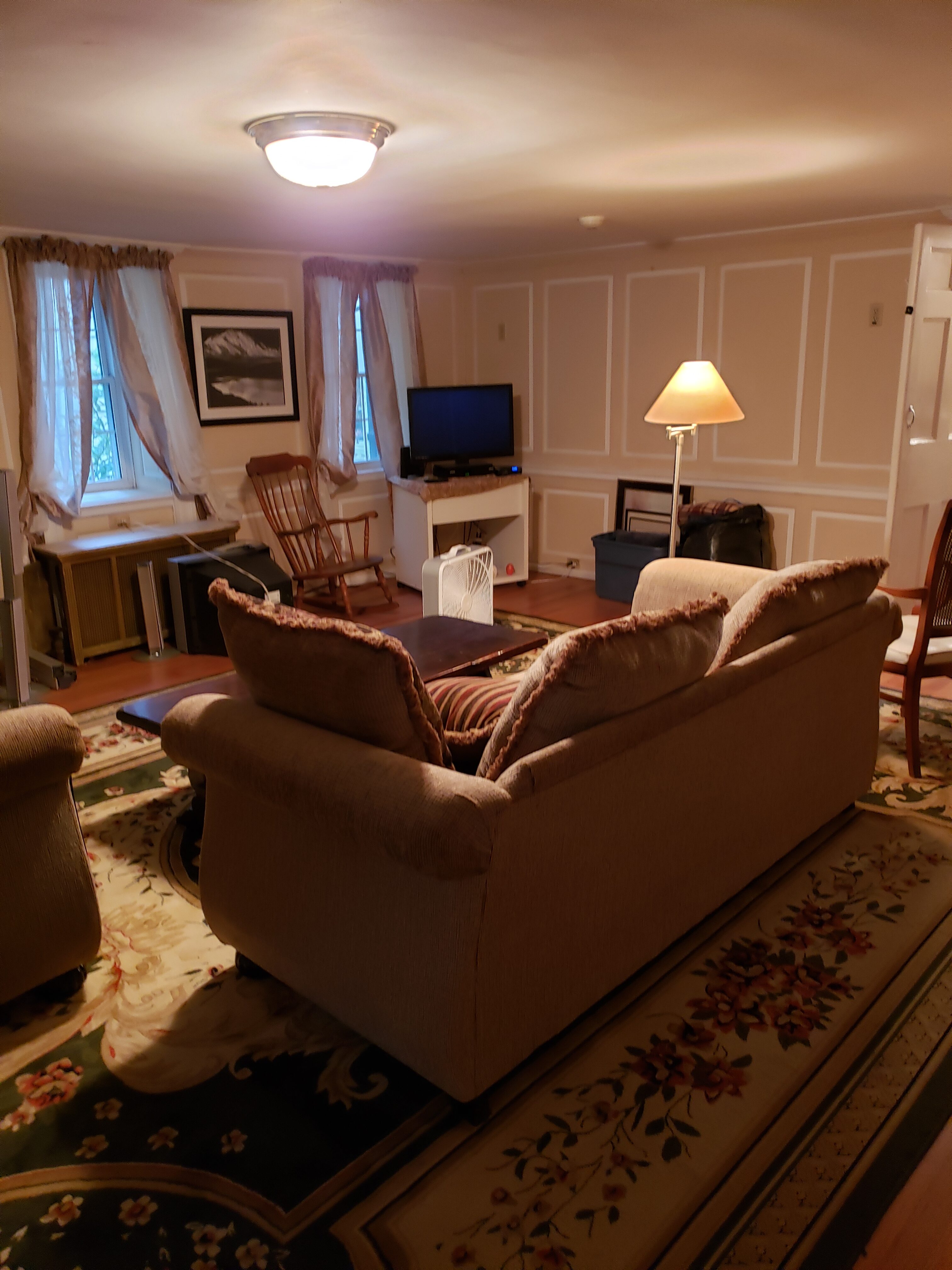 Comfortable living room with sofa, armchair, TV, and warm lighting.