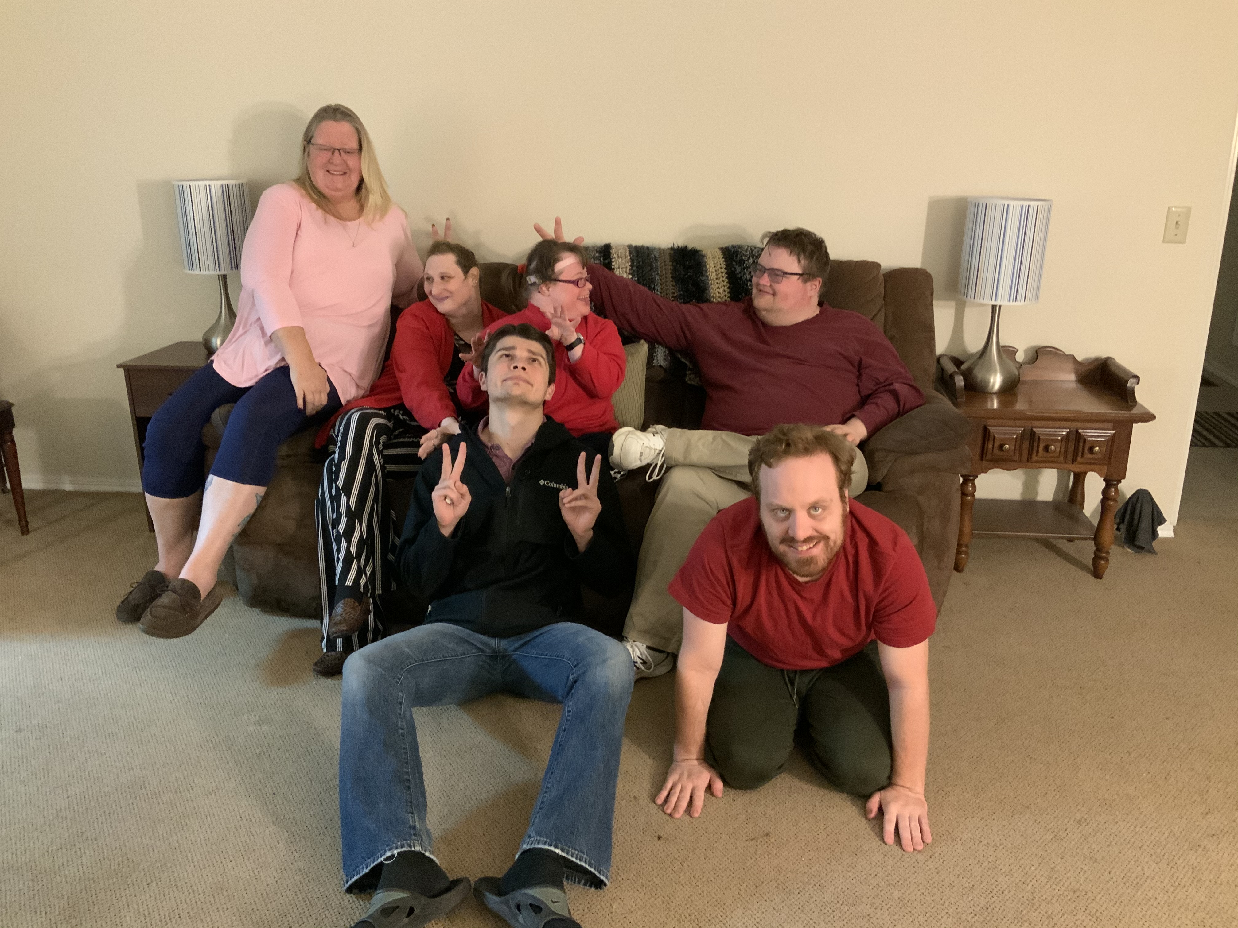 Group of diverse people posing together in a living room setting.