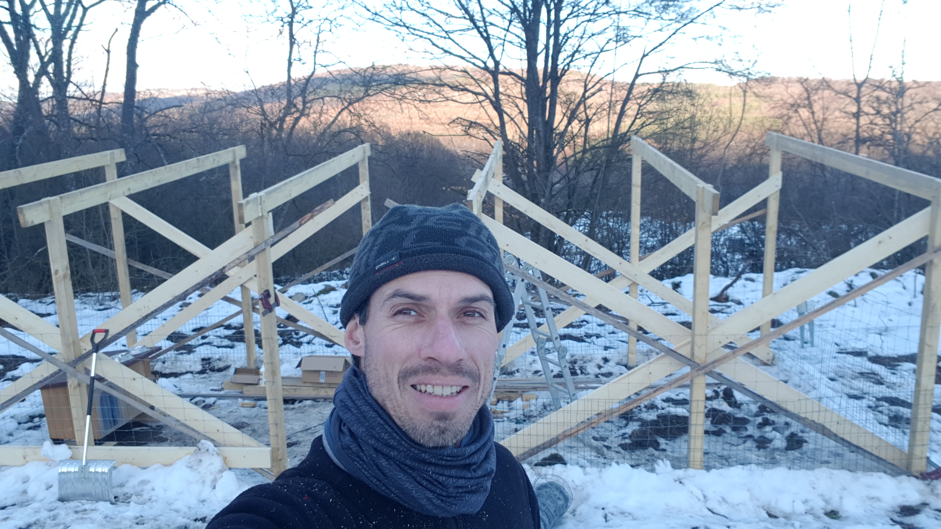 Man working on wooden construction at farm during winter.