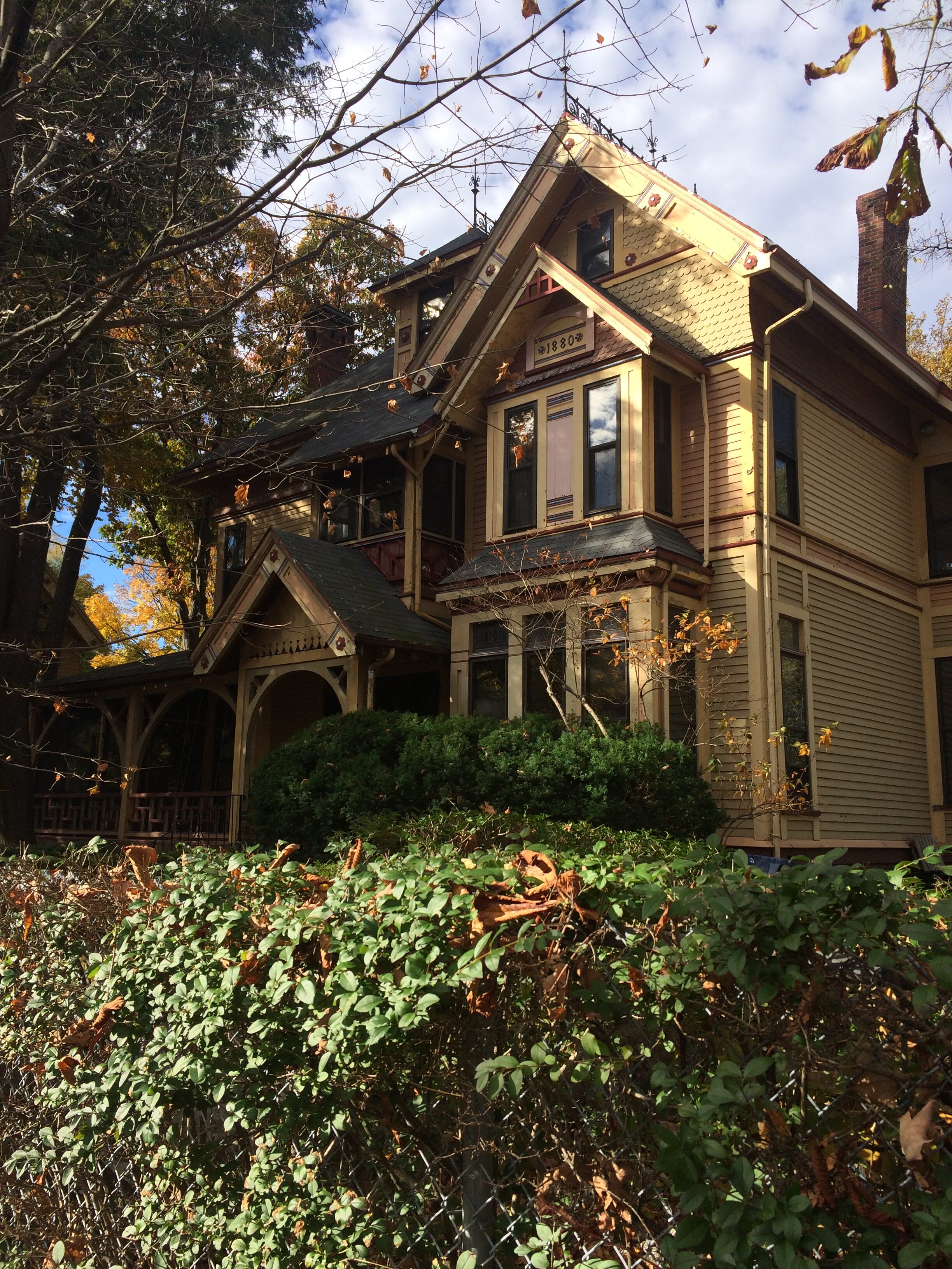 Victorian house surrounded by trees and autumn foliage.