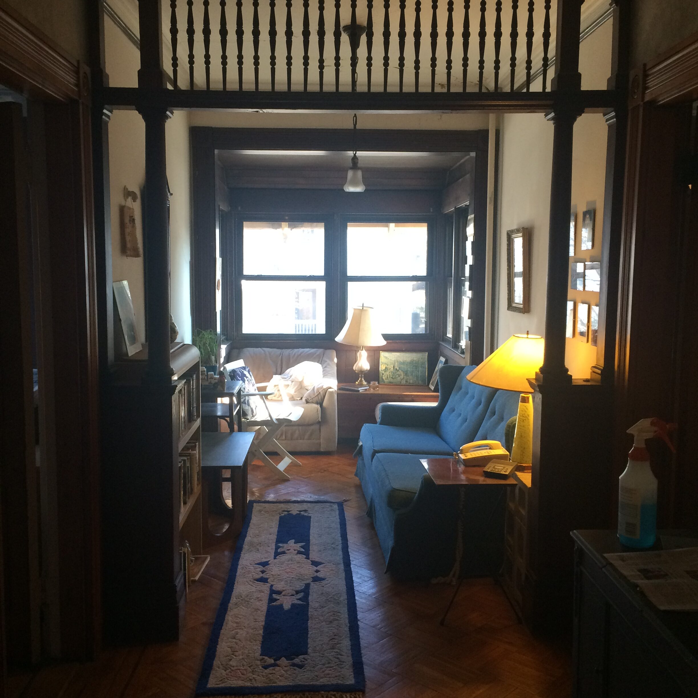 Interior of a vintage-style living room with sofas, lamps, and large windows.