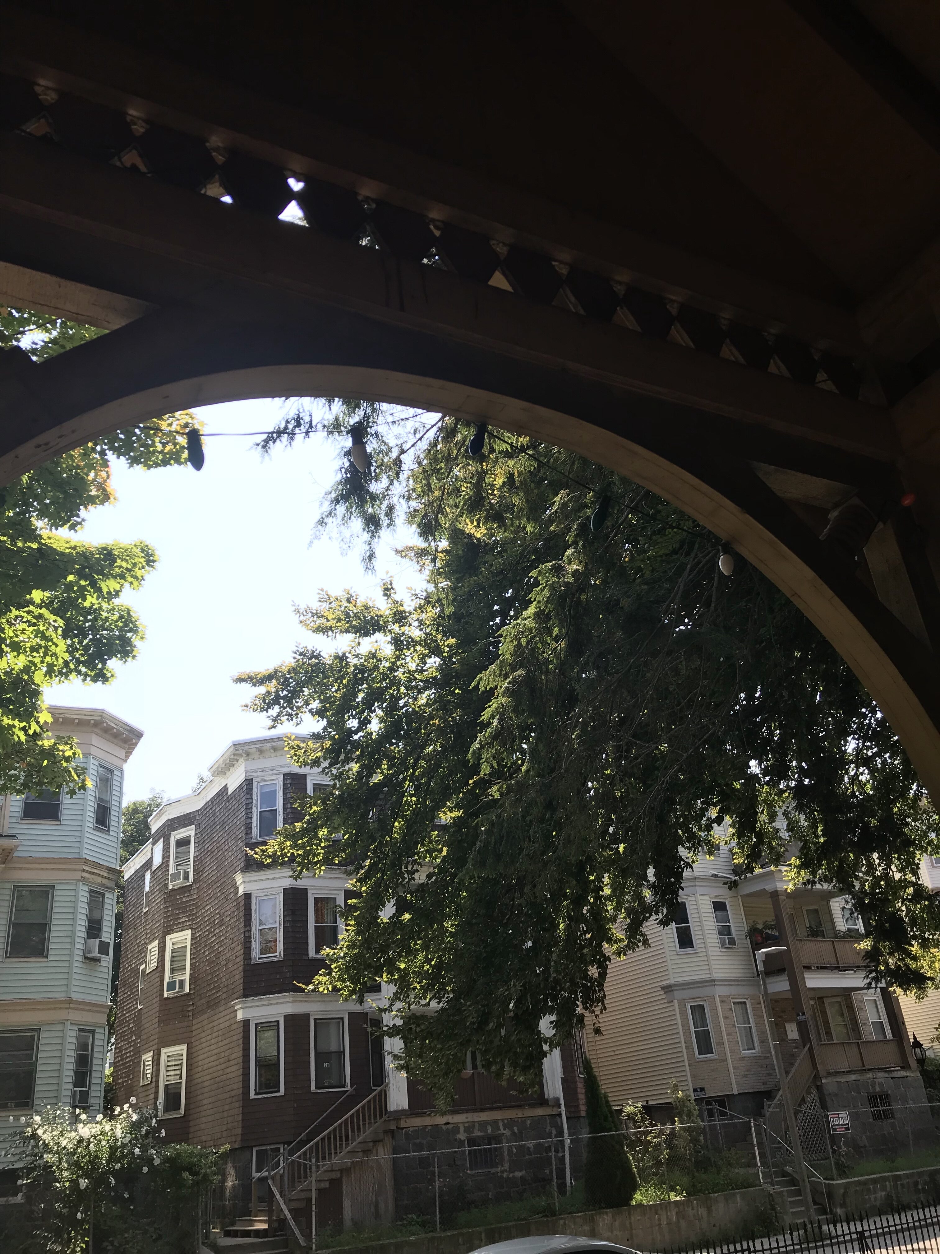 Residential buildings with tree canopy in a community setting.