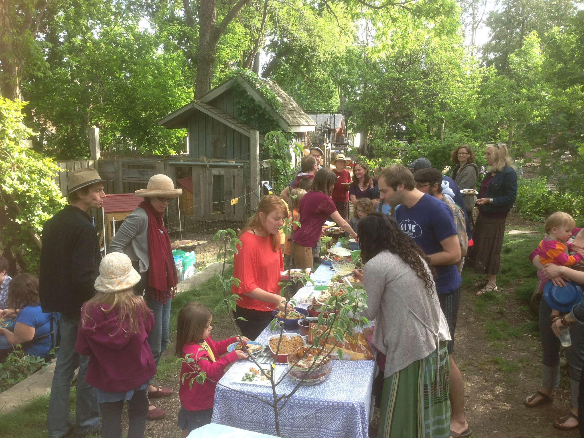 People enjoying a community outdoor event with tables and greenery.