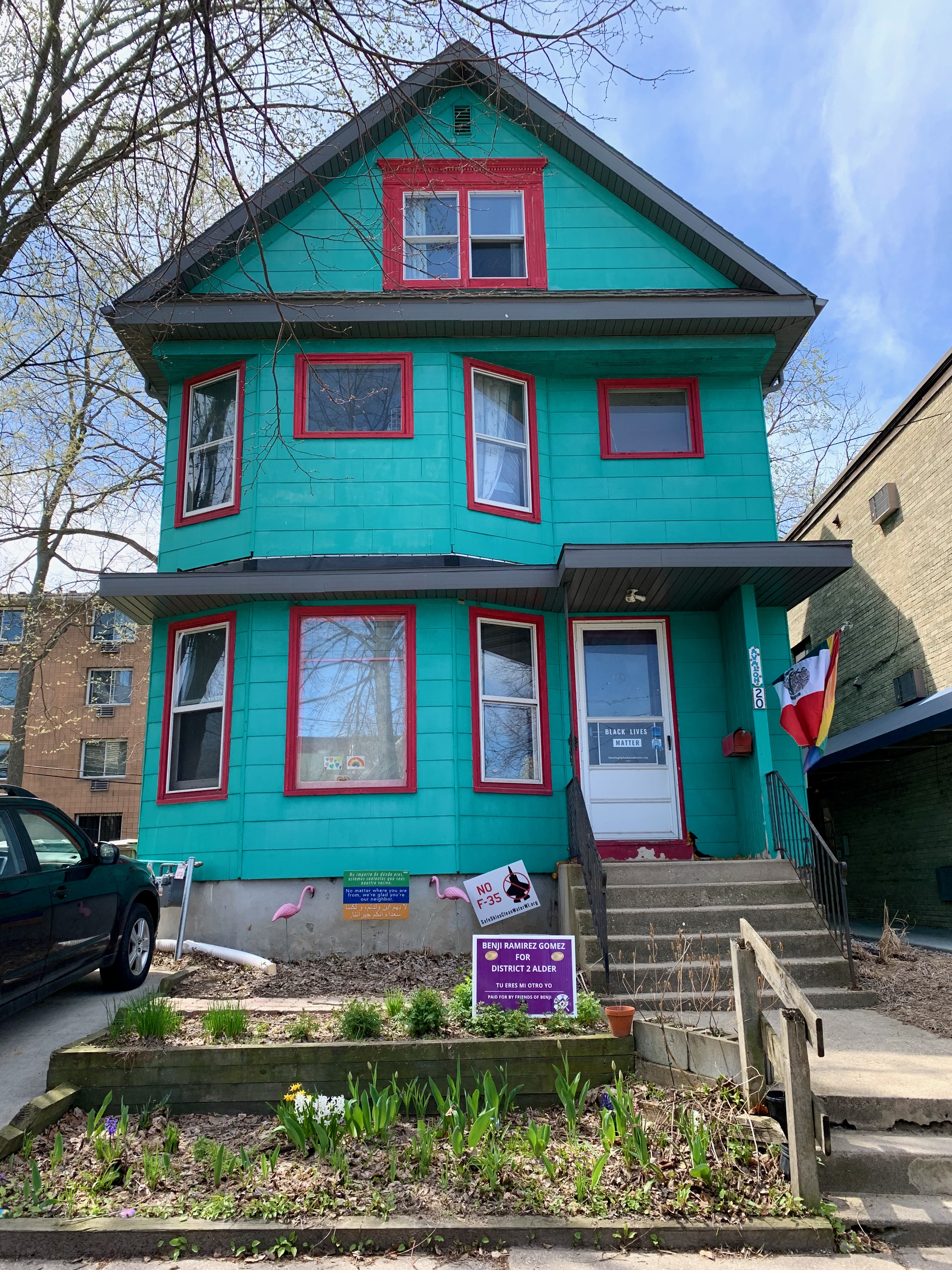 Vibrant turquoise house with red window frames in Portland, Oregon.