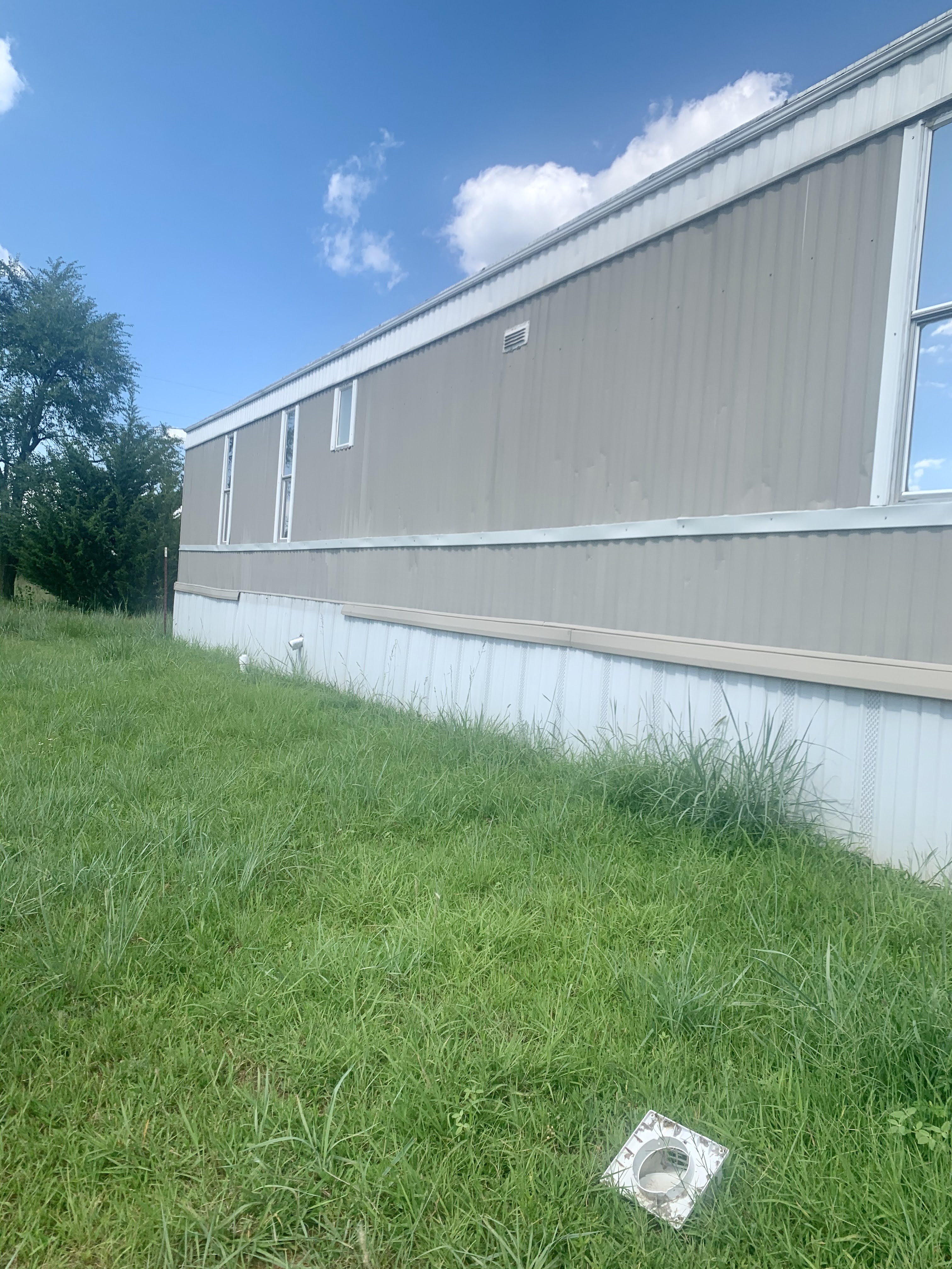 Mobile home with grassy yard and blue sky at IC Foundation.