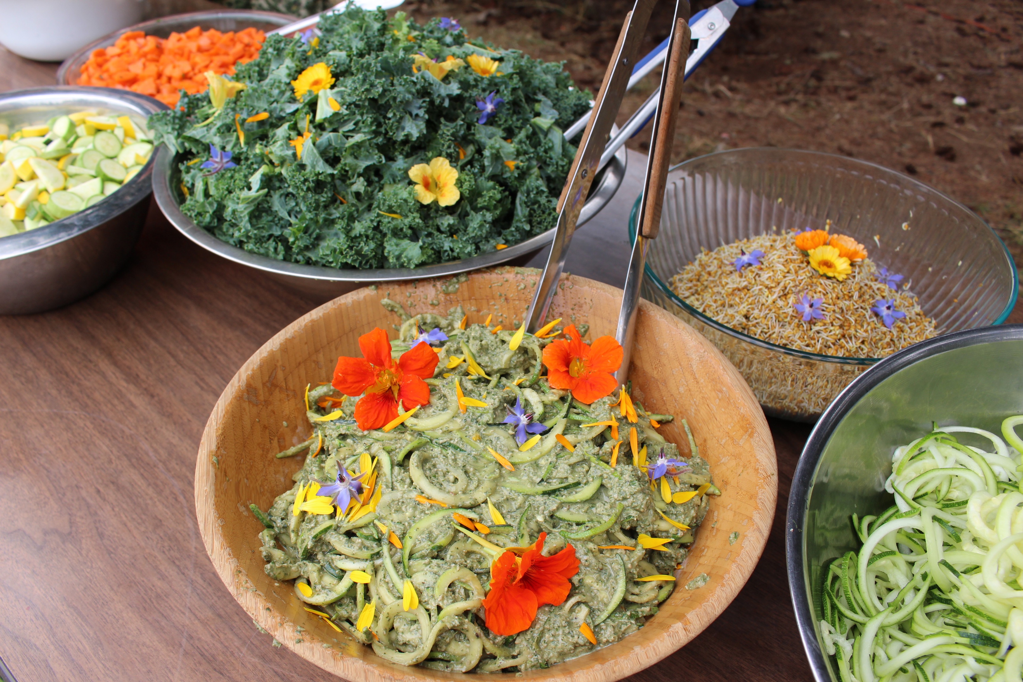 Colorful vegan salads with edible flowers and fresh vegetables for community gathering.