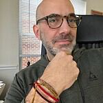 Man with glasses and beard in office, thoughtful pose.
