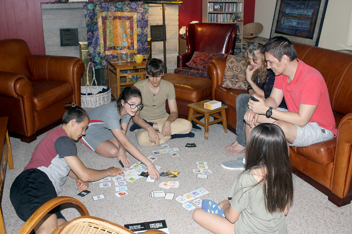 Group of people playing card games in a cozy living room setting.
