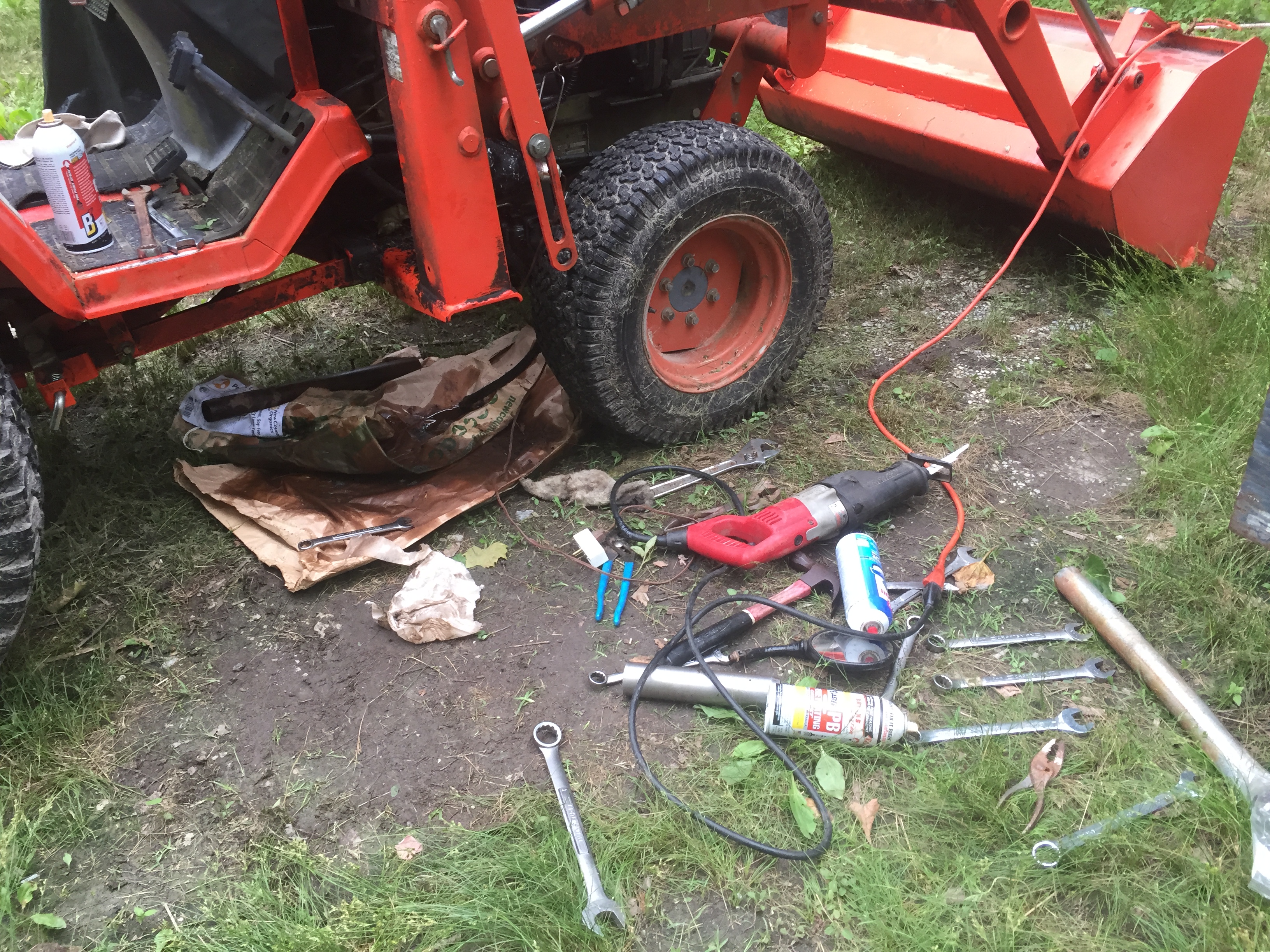 Tools and equipment for tractor repair on grassy ground.