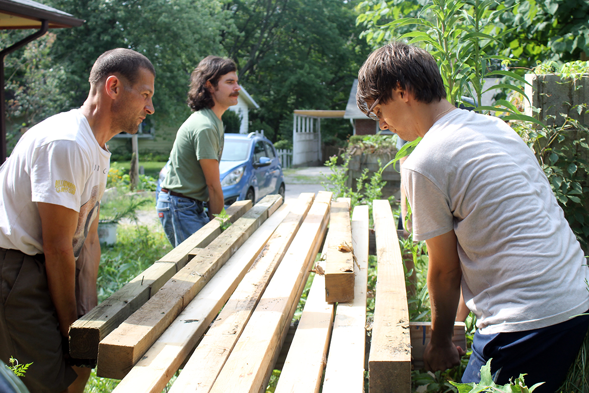 People working together on wooden construction in a community garden setting.