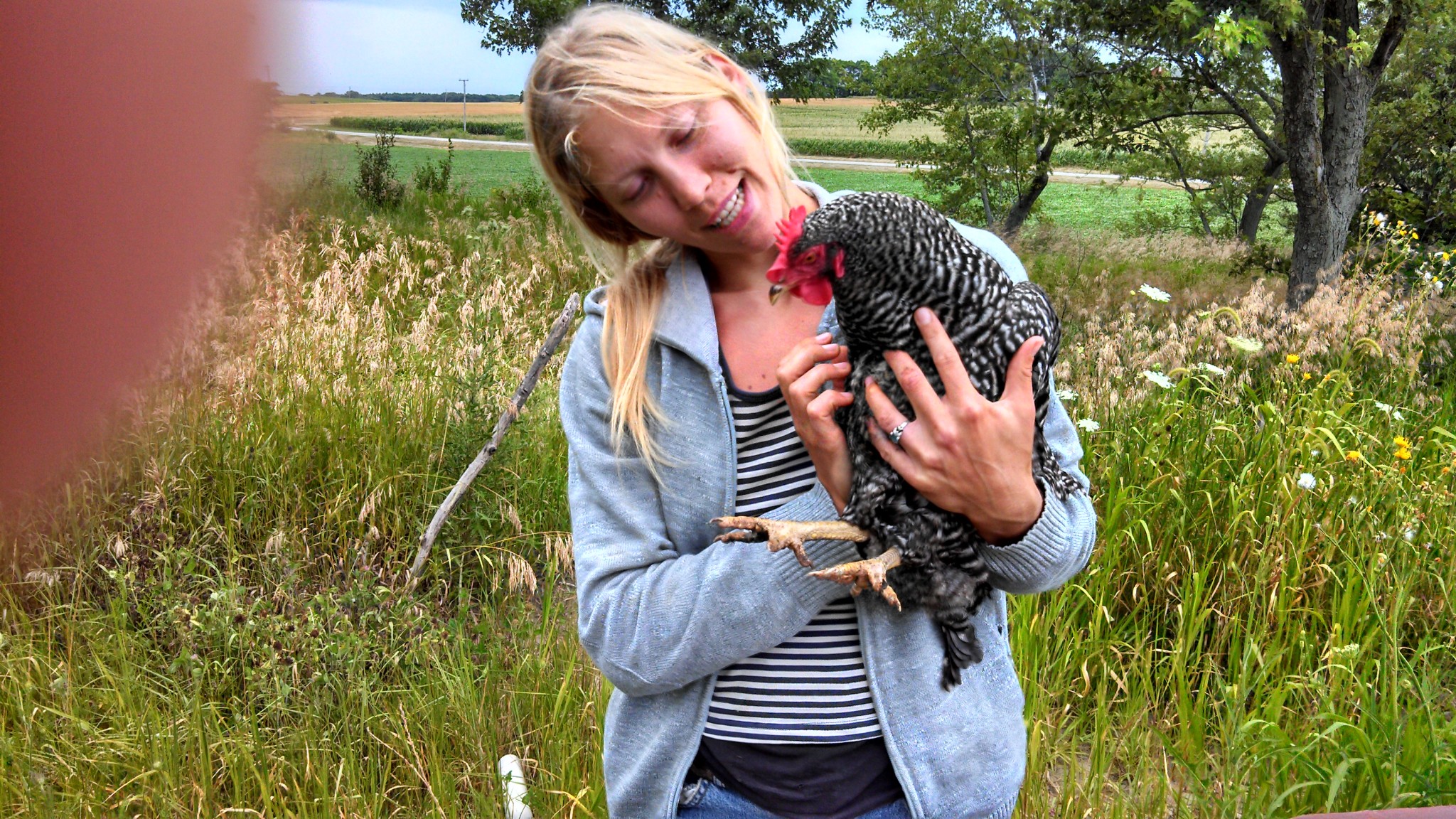 Woman holding a chicken in a rural farm setting for Foundation for Intentional Community.