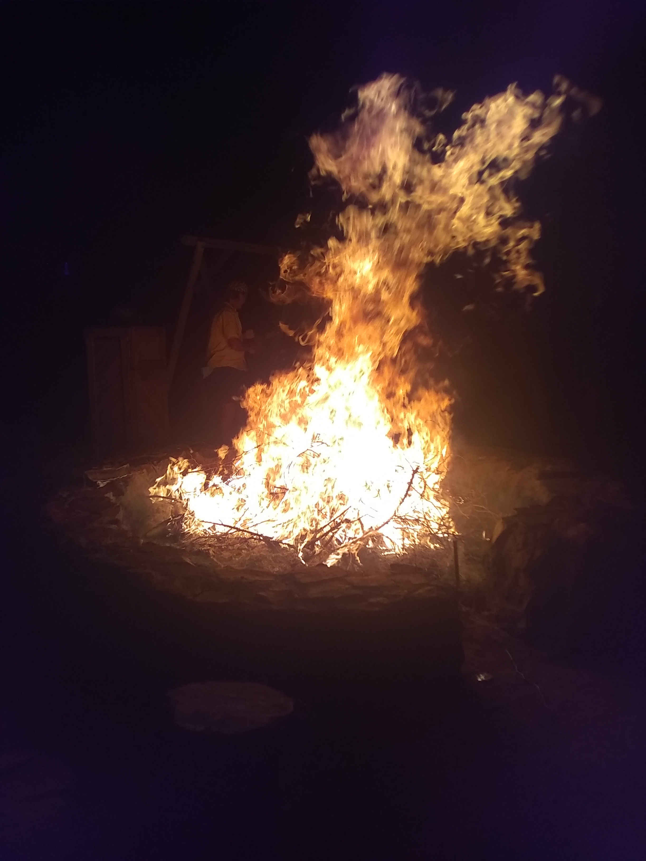Large bonfire burning brightly during night at intentional community event.