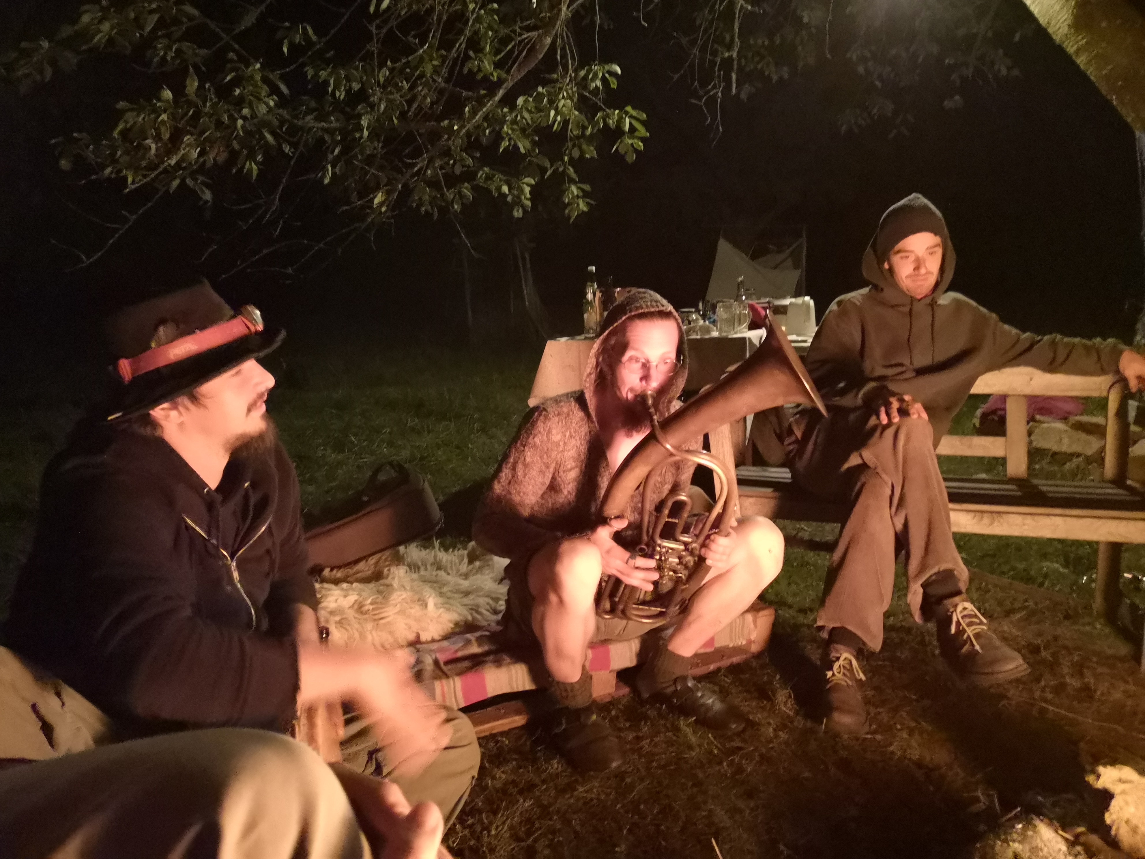People sitting around a campfire at night in a community setting.