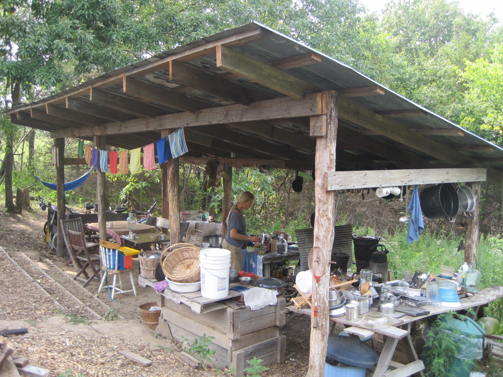 Rustic farm shelter with kitchen and outdoor dining area in a community setting.
