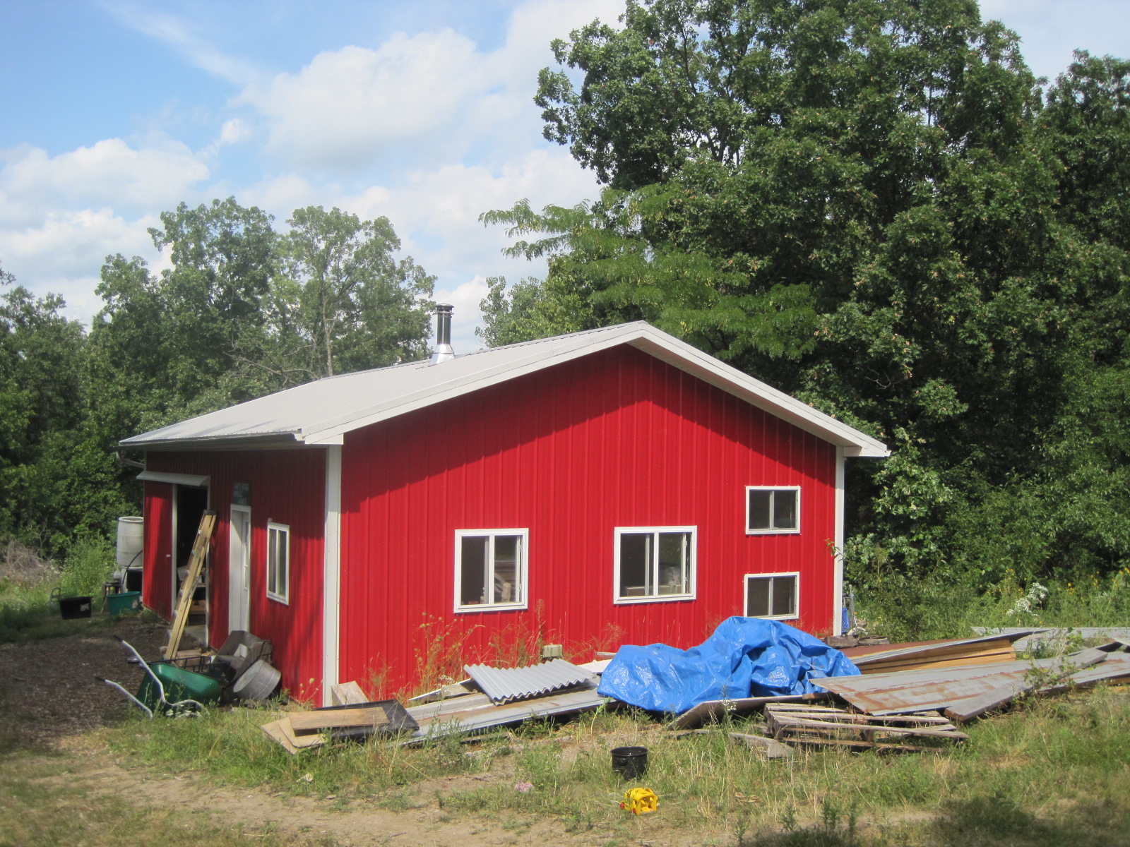Red barn at Foundation for Intentional Community farm with trees and blue sky.