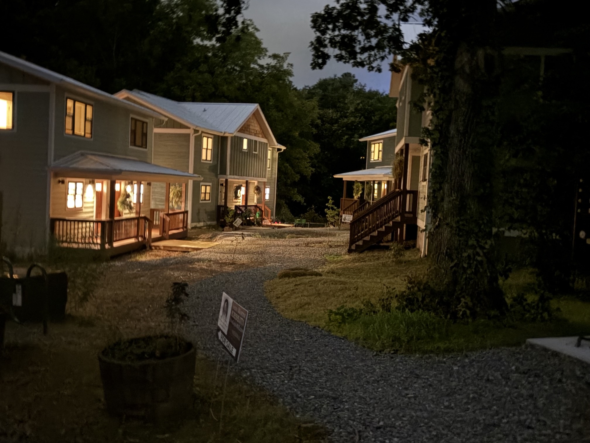 Night view of eco-friendly community homes with warm lights and natural surroundings.