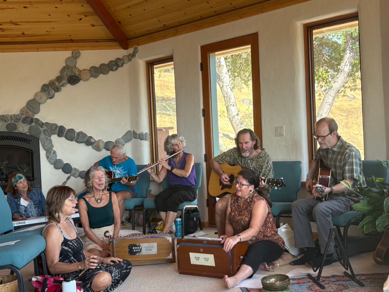 Group of people playing instruments and singing in cozy indoor setting.