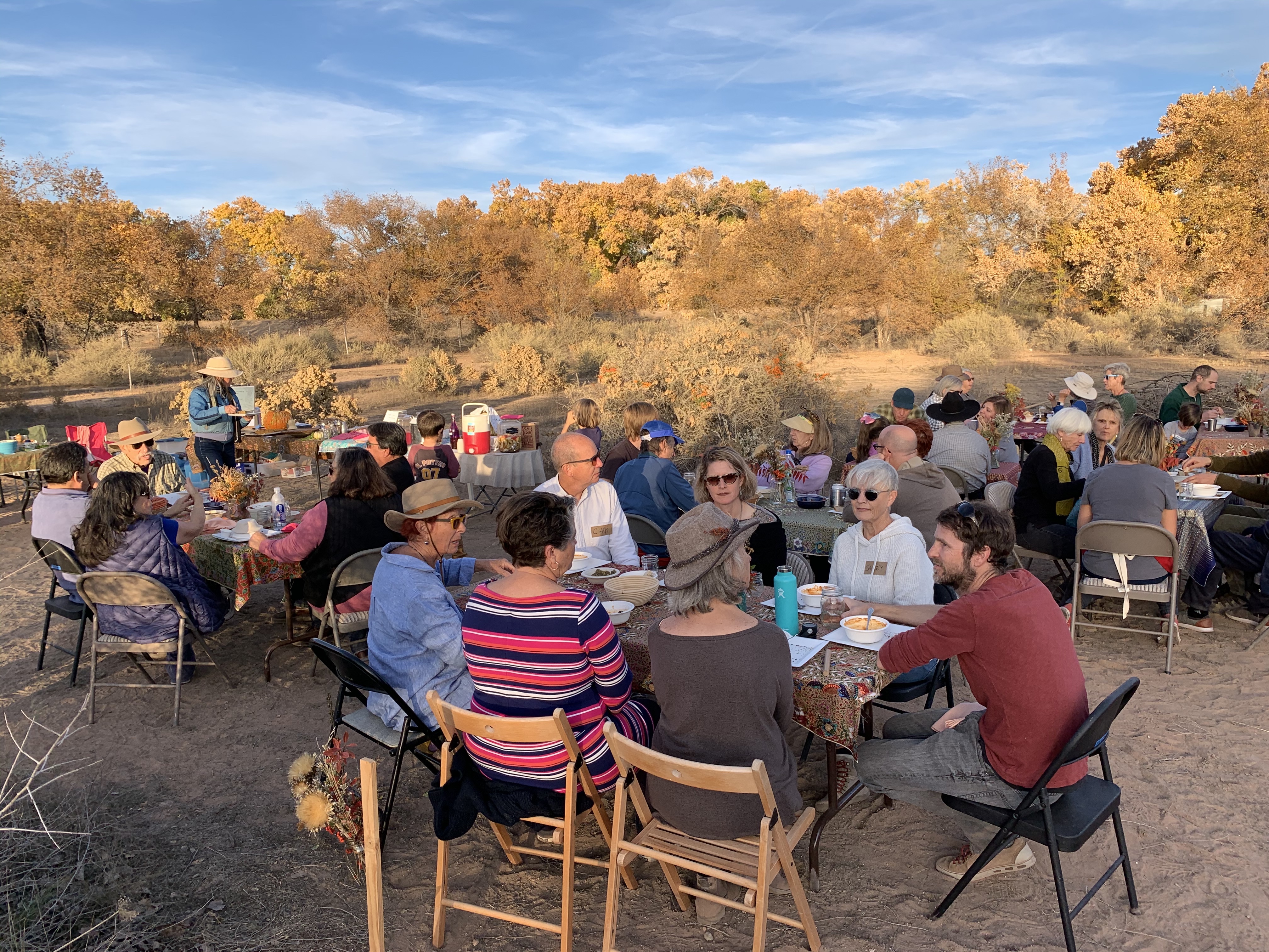 People gathered outdoors for a community event in autumn scenery.