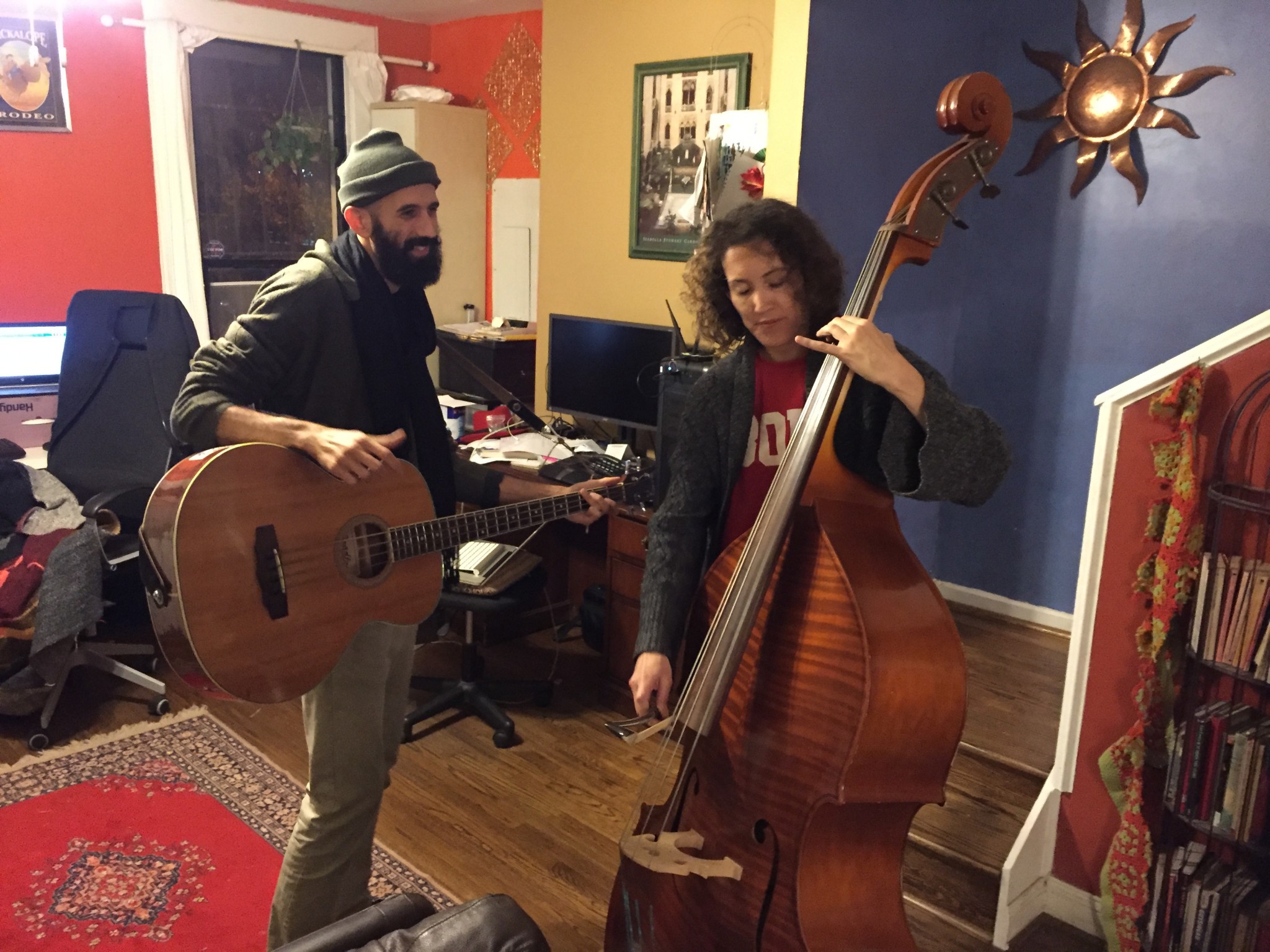 Two musicians playing guitar and double bass in a cozy room.