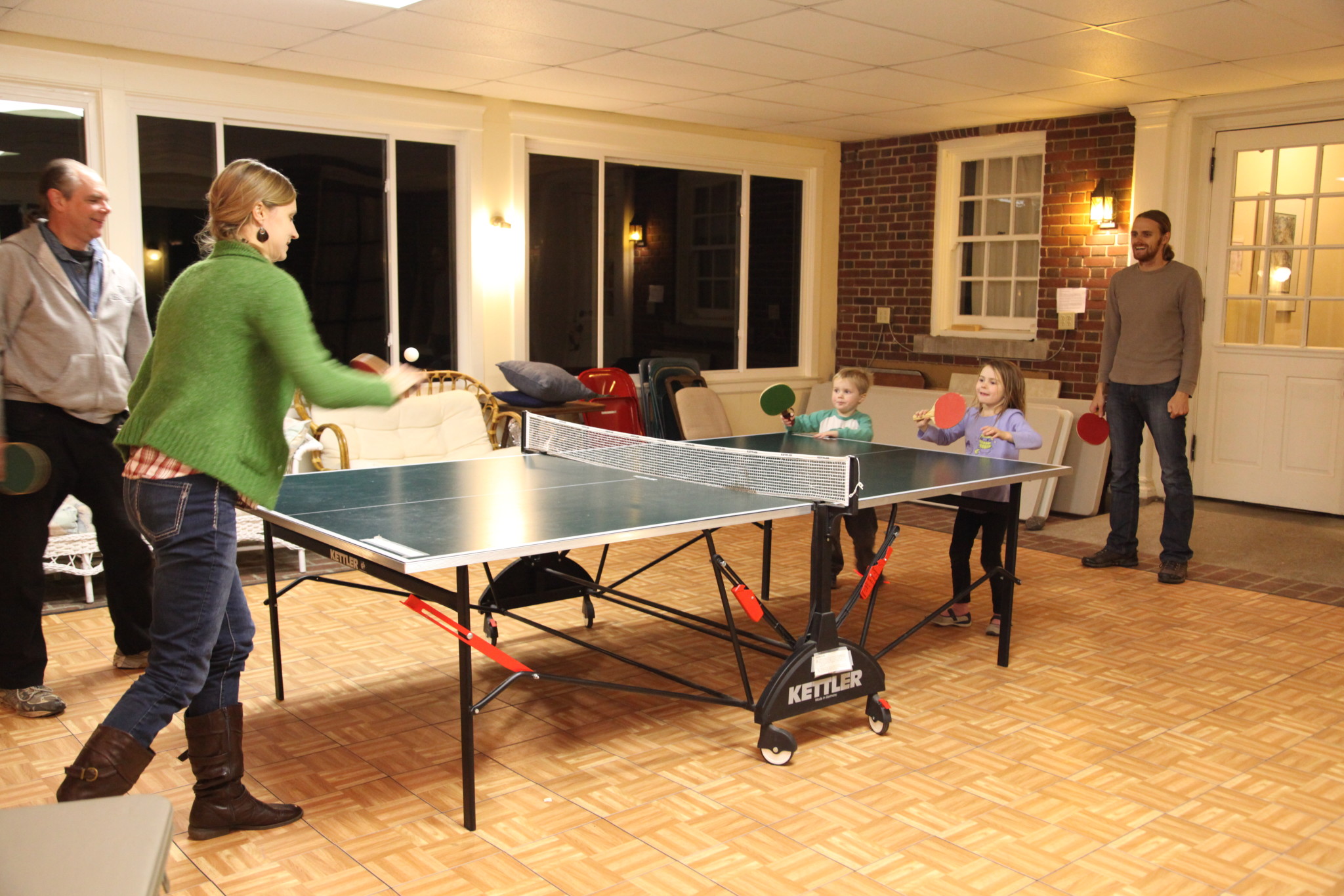 People playing ping pong indoors at a community event.