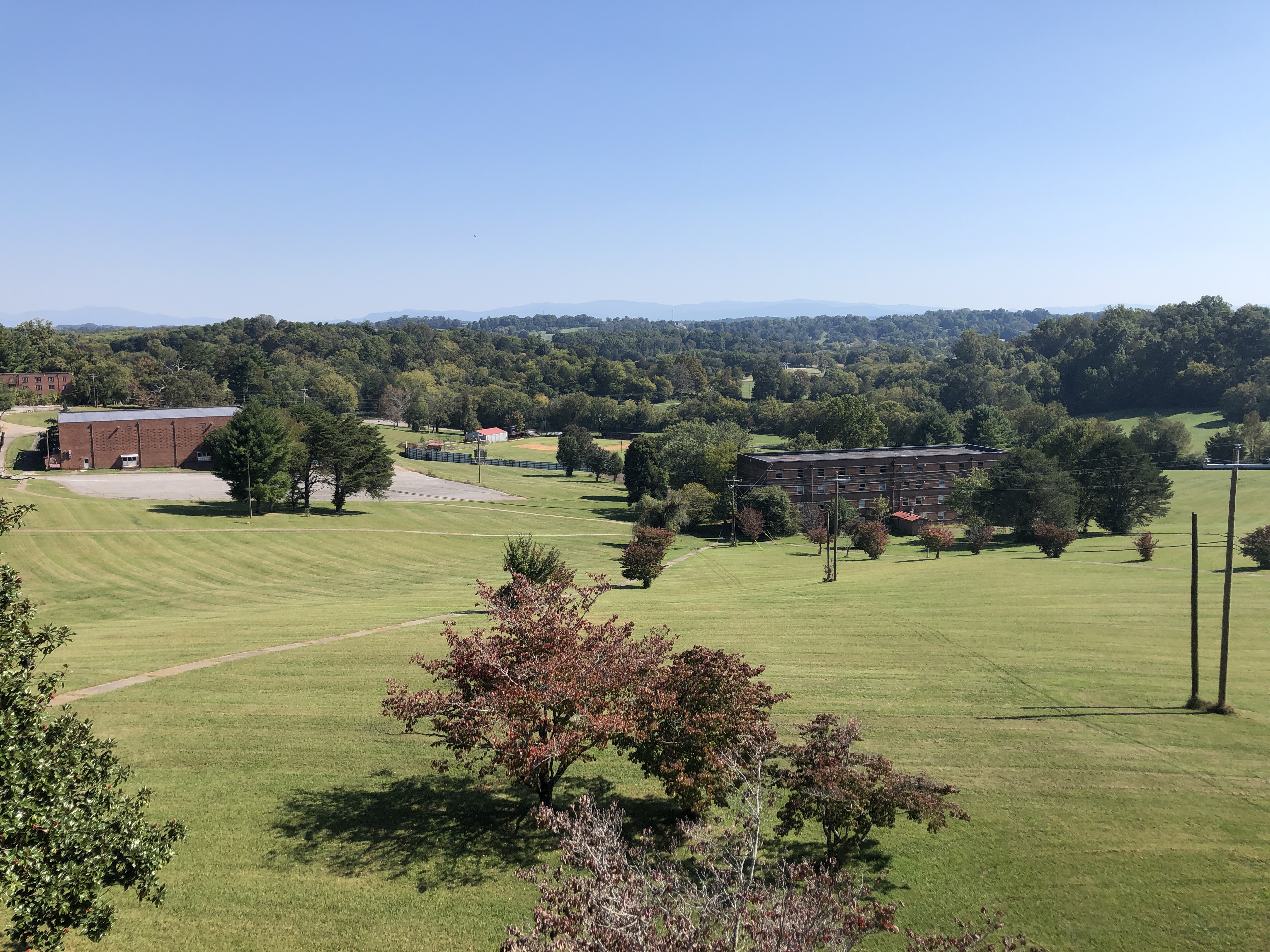 Scenic view of Hiwassee Bruderhof Community with green fields and trees.