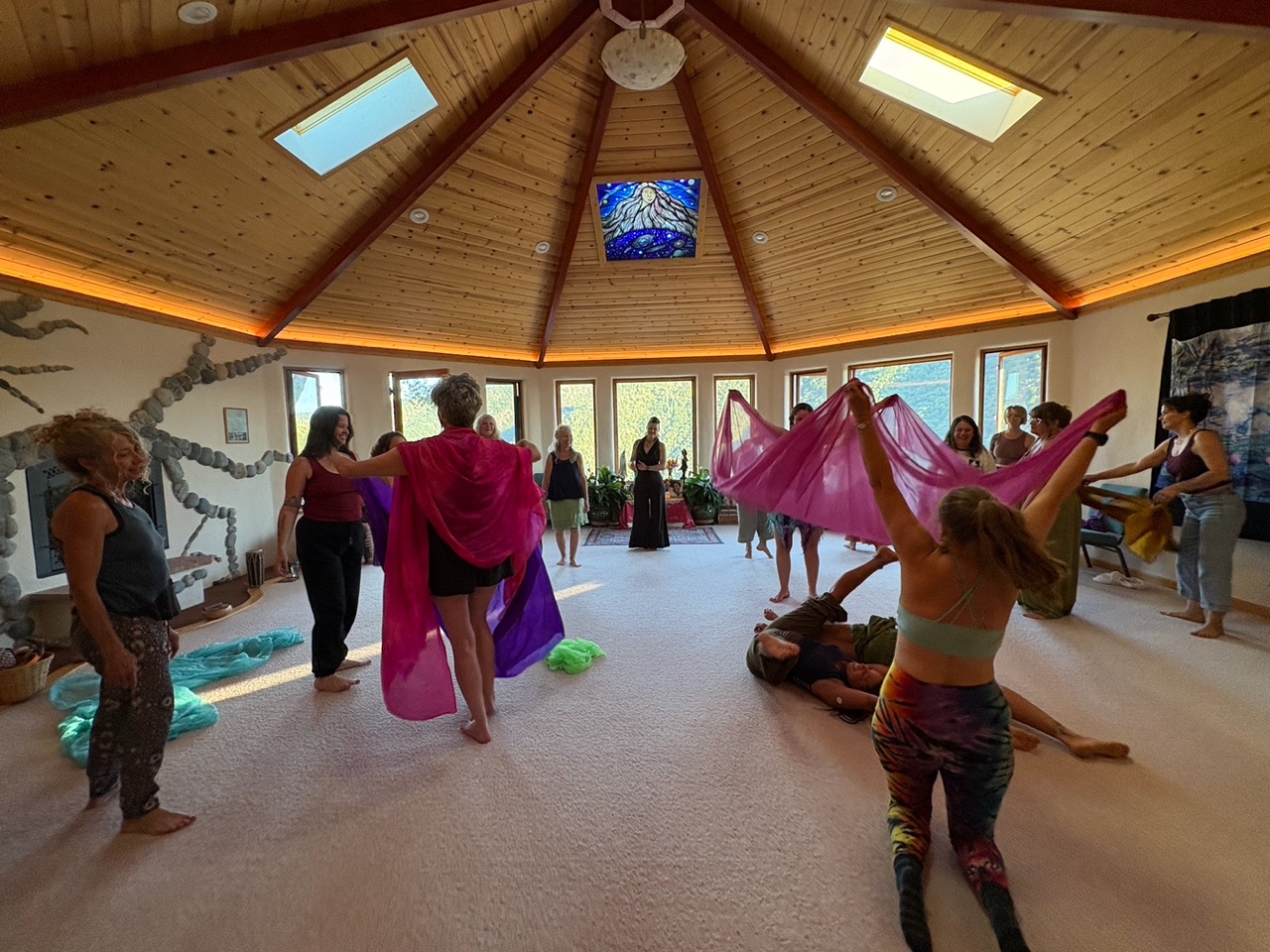 People participating in a community dance or workshop in a round wooden room.